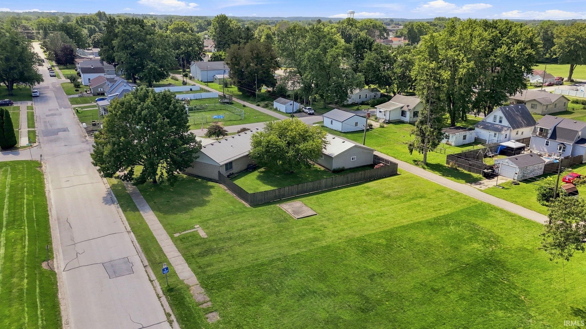 Expansive grassy lot bordered by a sidewalk and paved street