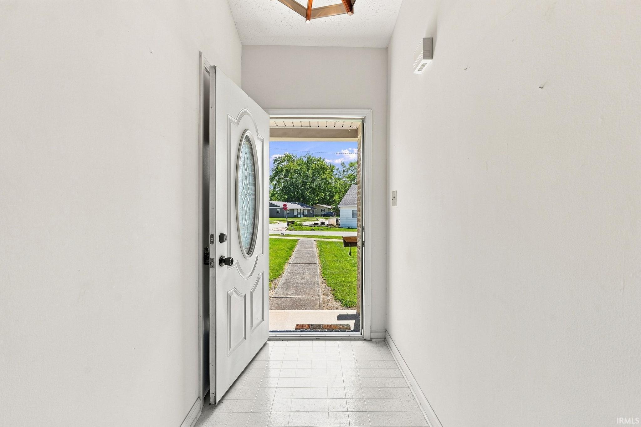 White paneled entry door with an oval decorative glass insert