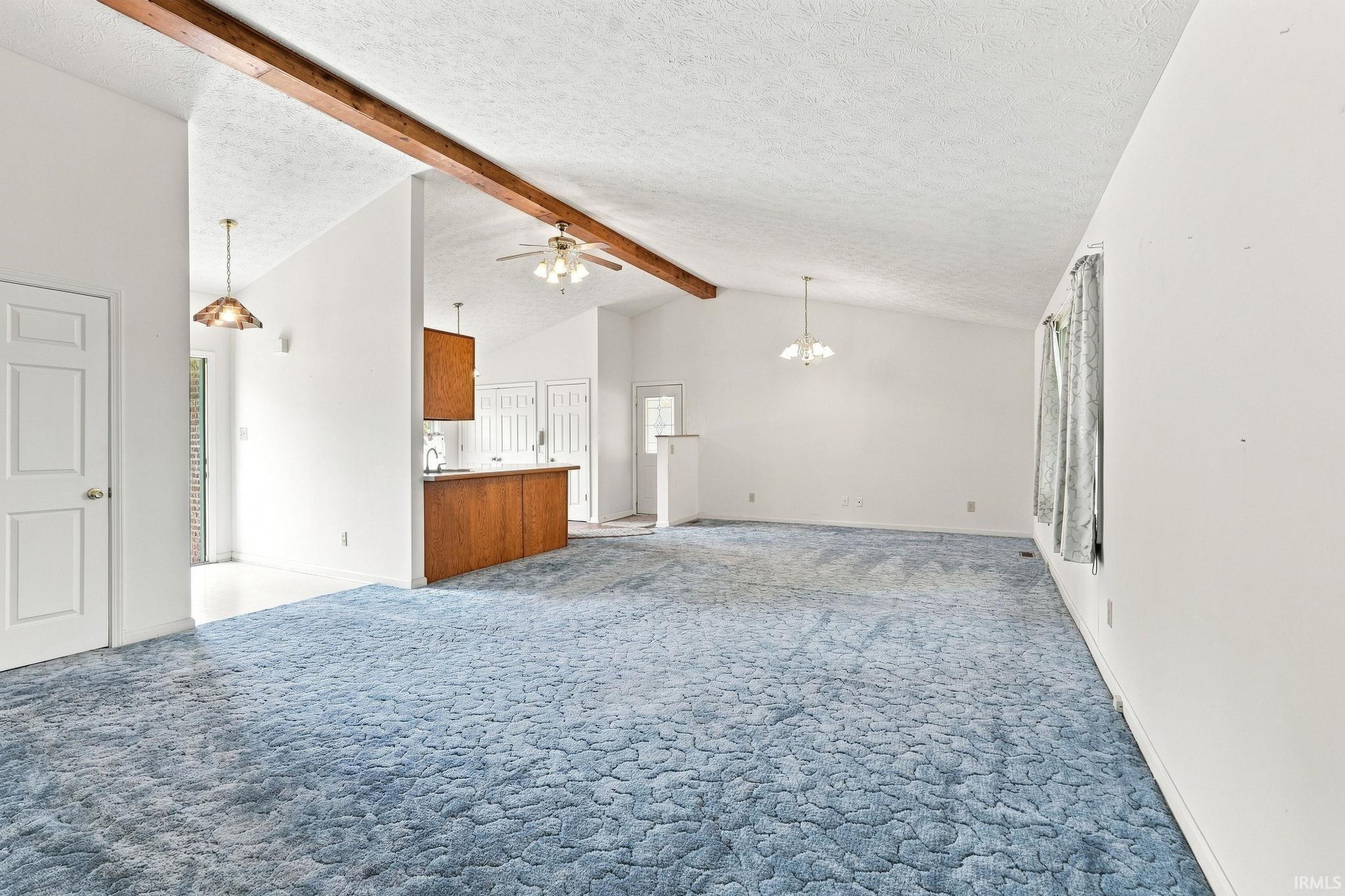 Vaulted ceiling with exposed wood beams, ceiling fan, and pendant lighting