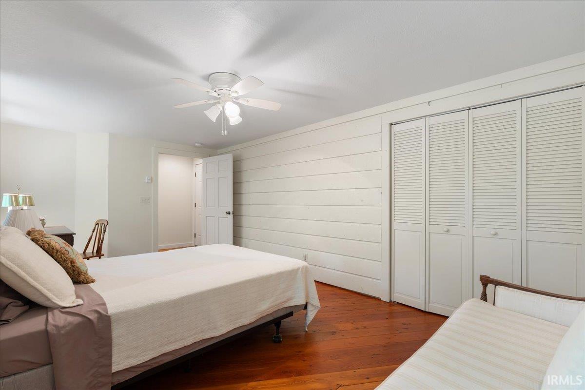 Wood-finish flooring, white shiplap wall, and bi-fold louvered closet doors