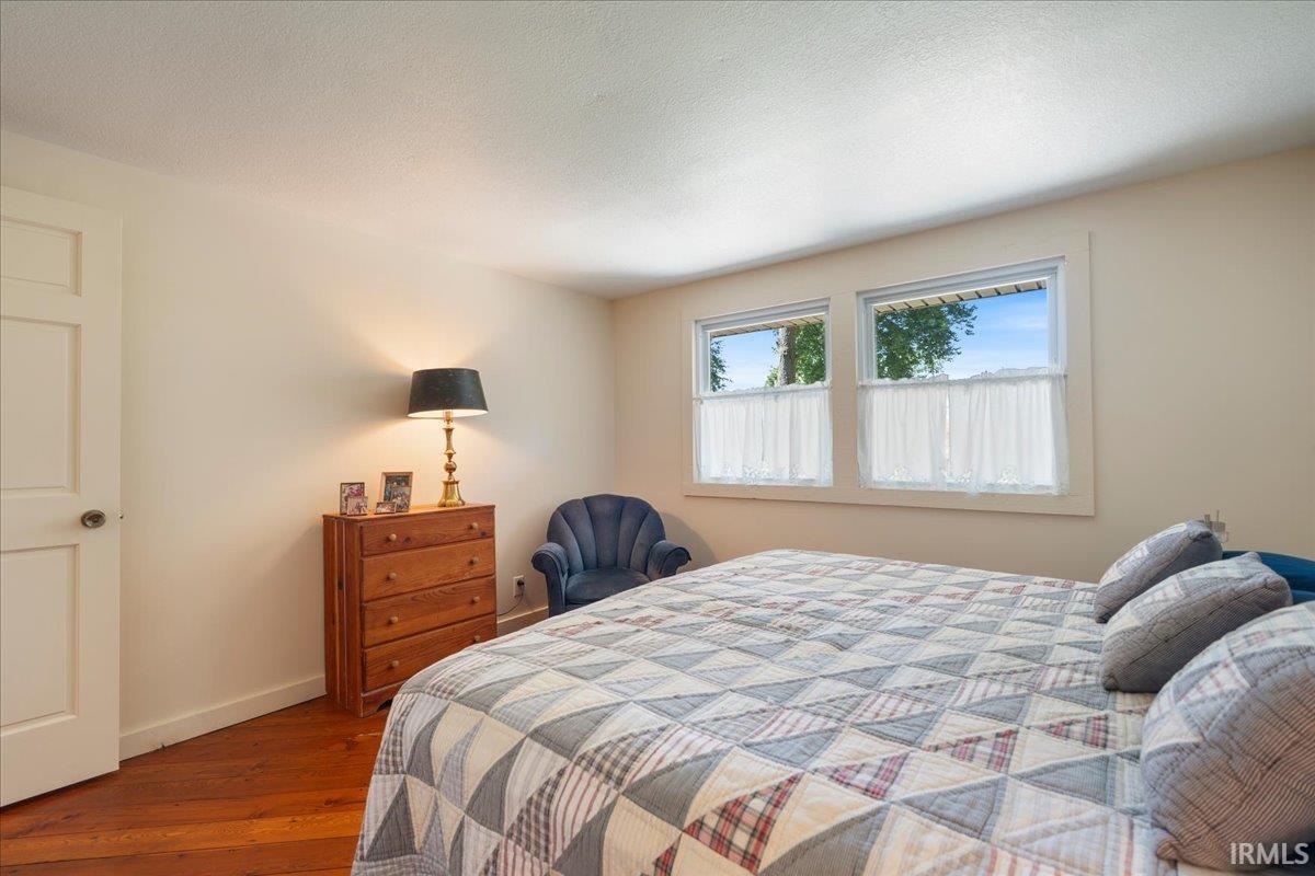 Warm-toned wood flooring, crisp white trim, and two bright windows