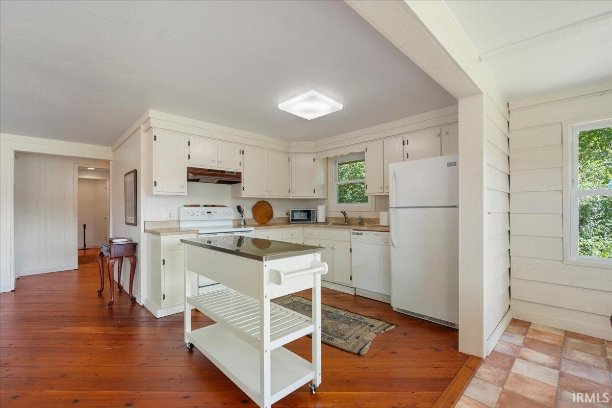 Kitchen featuring white cabinetry, light-toned countertops, wood-finish flooring, and a tiled floor section