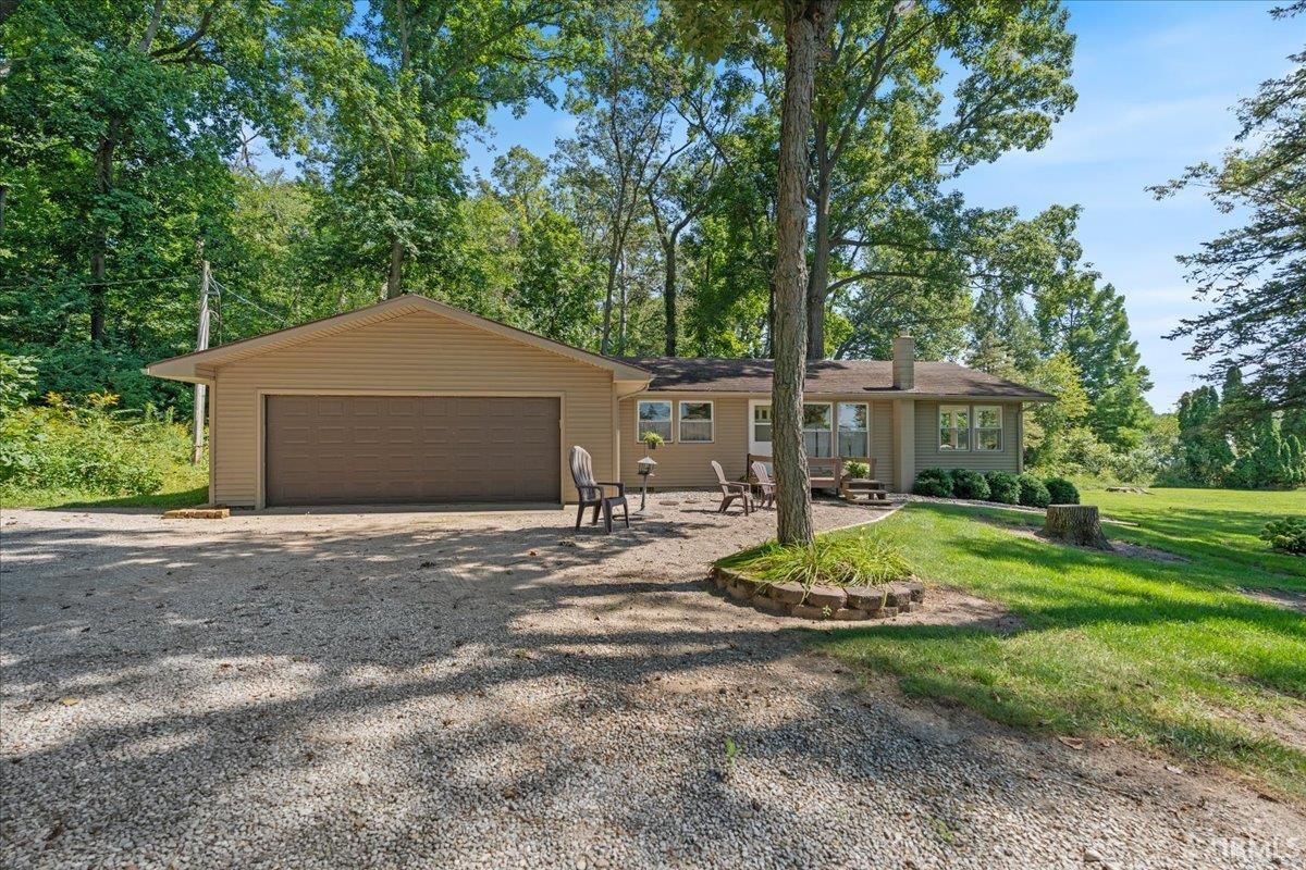 Single-story residence with a two-car garage, gravel driveway, and a stone-edged planting bed