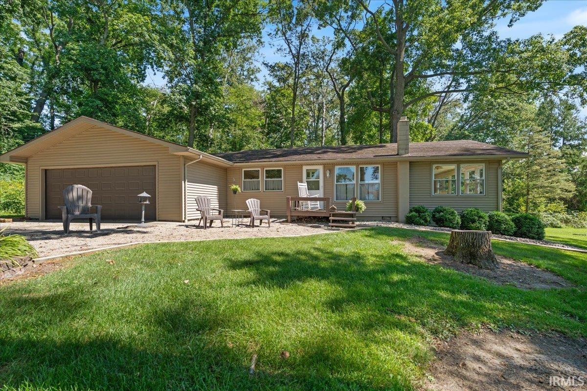 Ranch-style exterior with tan siding, integrated two-car garage, and a front patio area