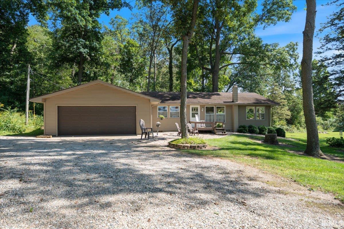 Ranch-style exterior with tan siding and a gravel driveway