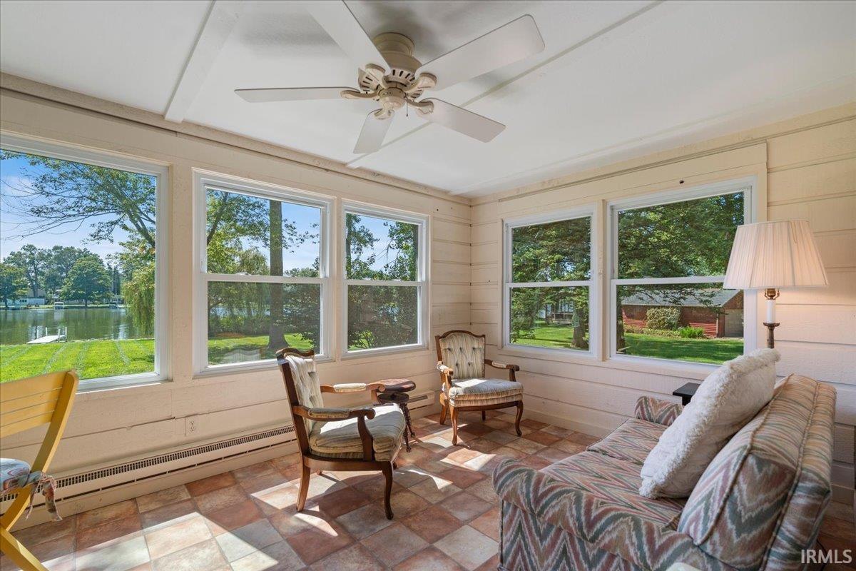 Sunroom with multiple windows, a ceiling fan, and tiled flooring