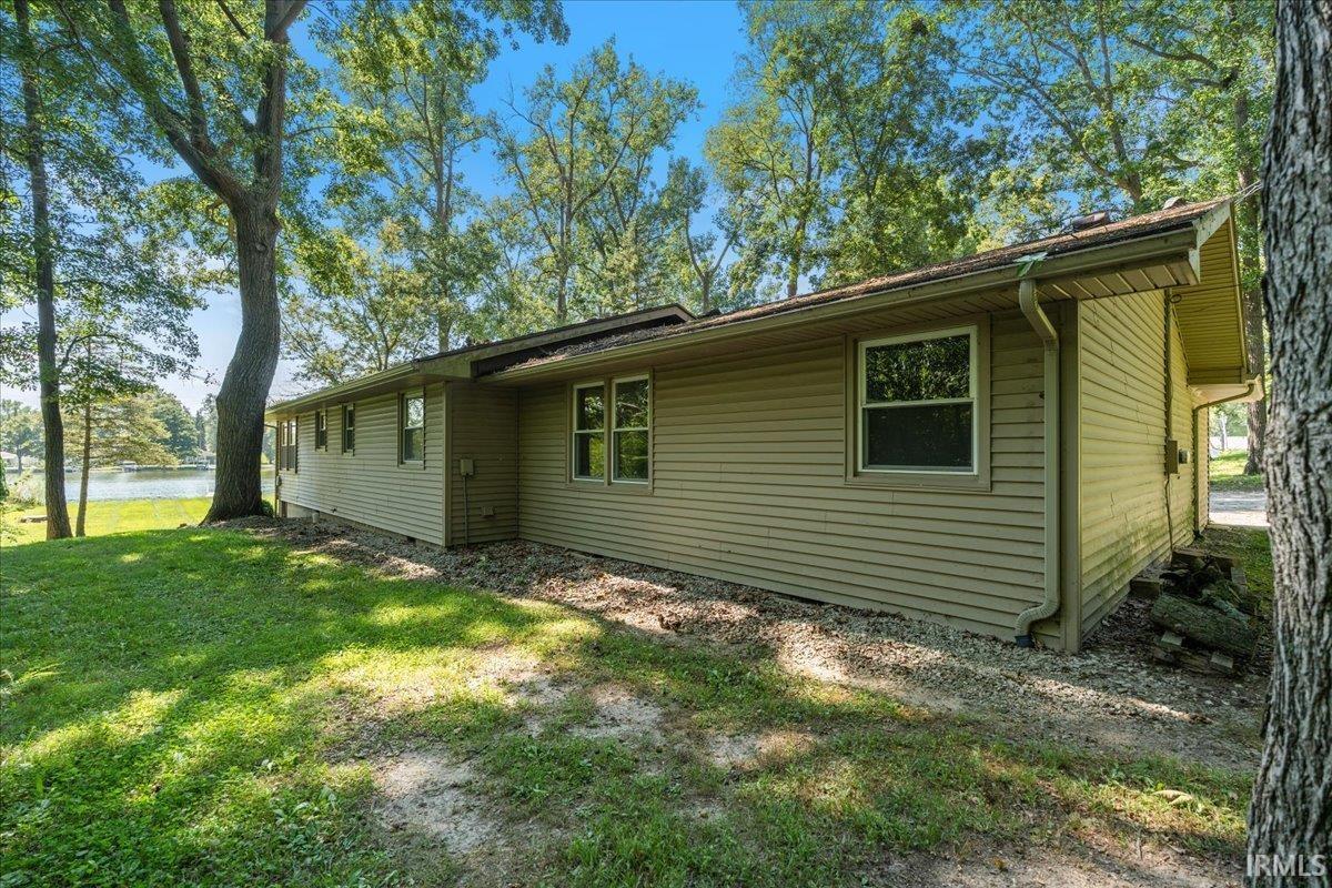 Exterior siding in a neutral tone, mature trees, and a visible body of water