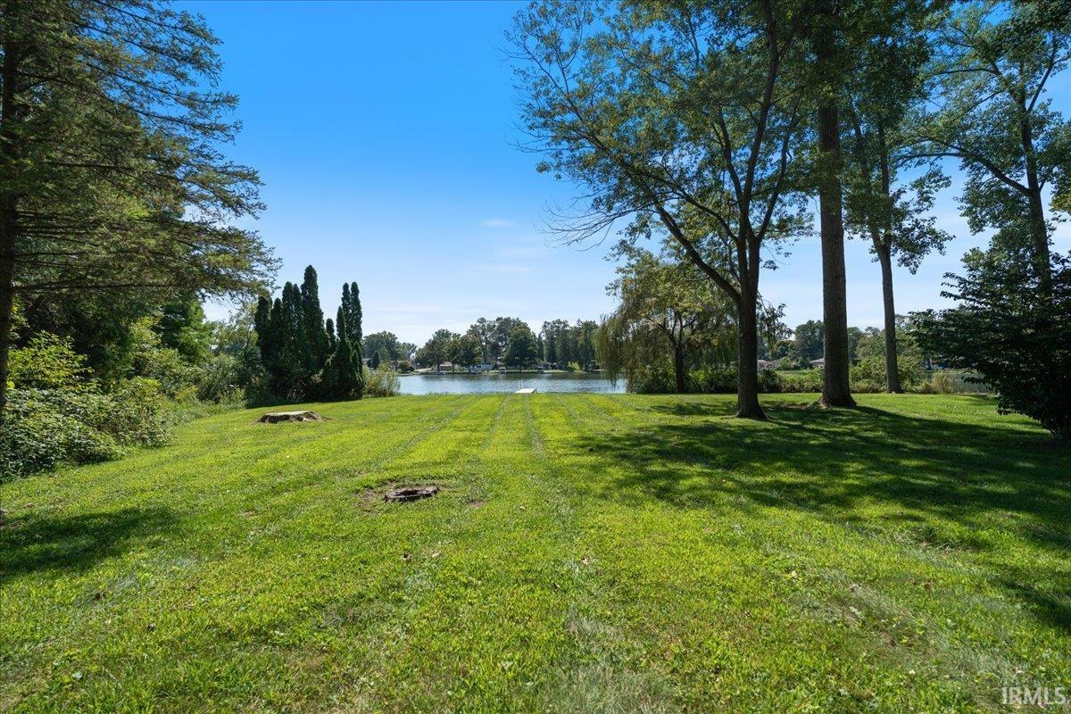 Expansive lawn with mature trees, direct water access, and a clear blue sky