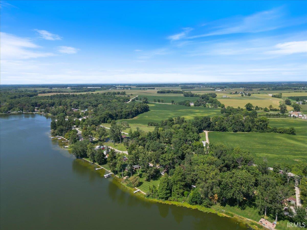 Lakeside property with mature trees, established residential areas, and expansive agricultural fields
