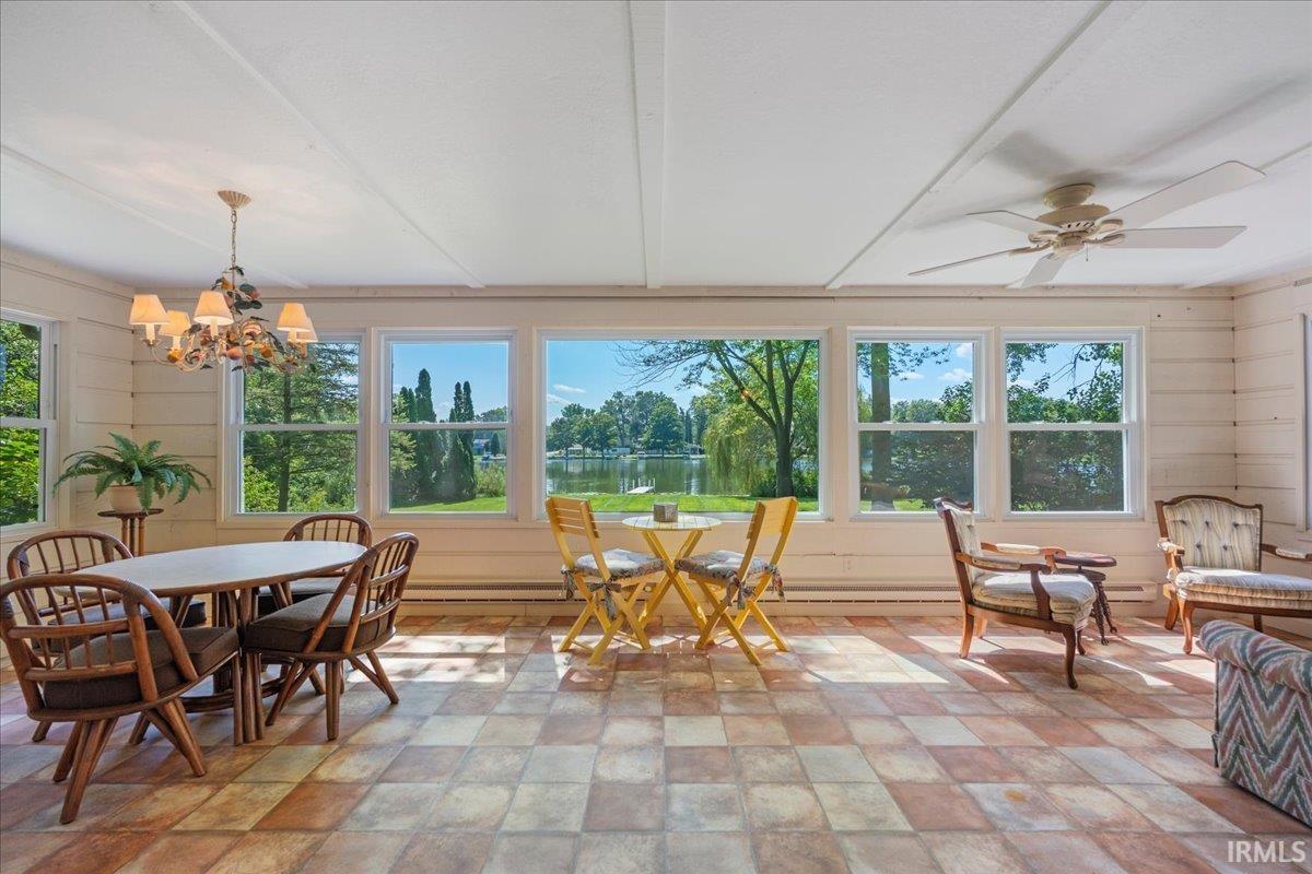 Sunroom with checkered tile flooring, multiple windows, a ceiling fan, and a chandelier