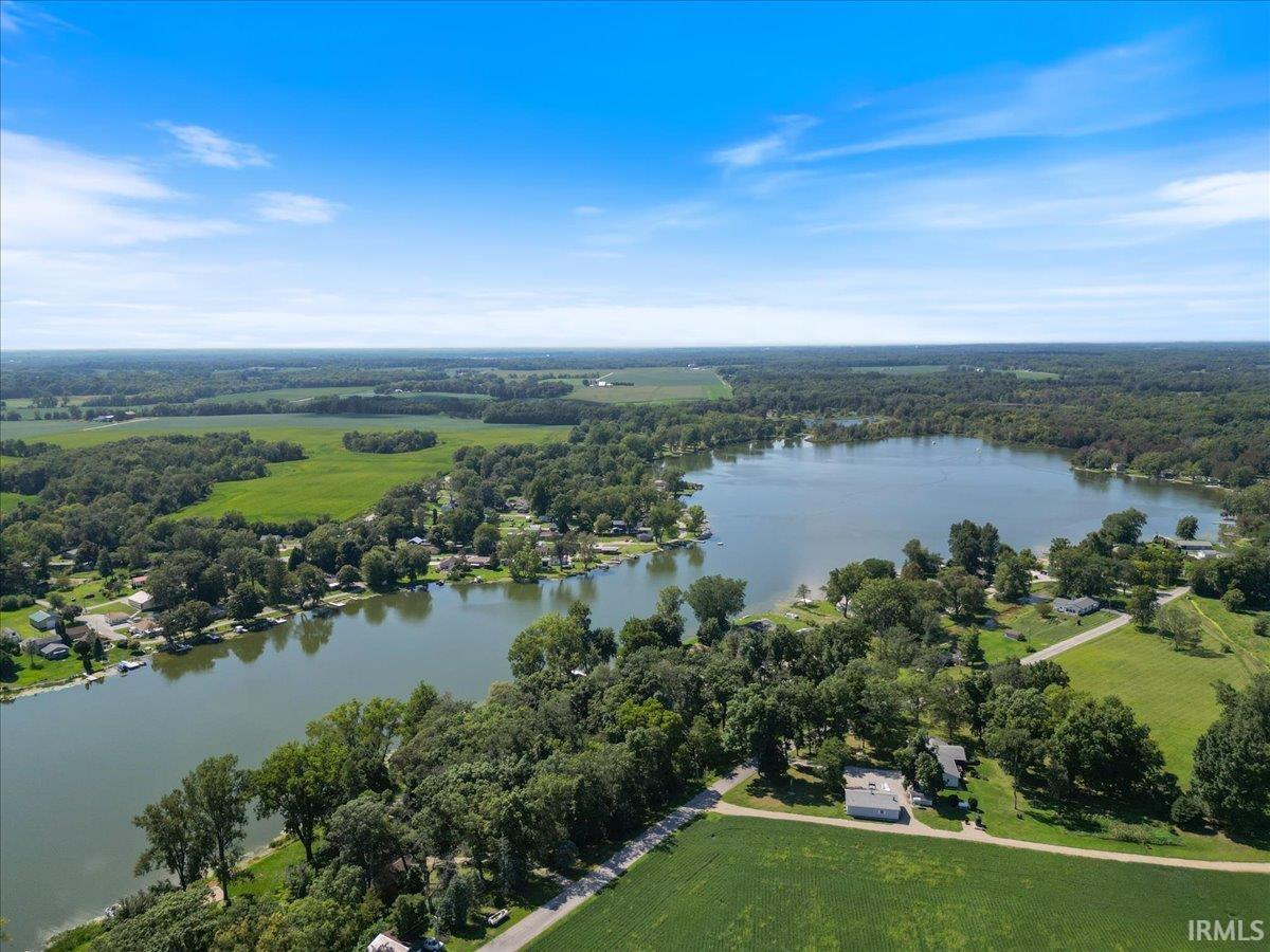 Expansive aerial showcasing a large lake, surrounding greenery, and agricultural fields