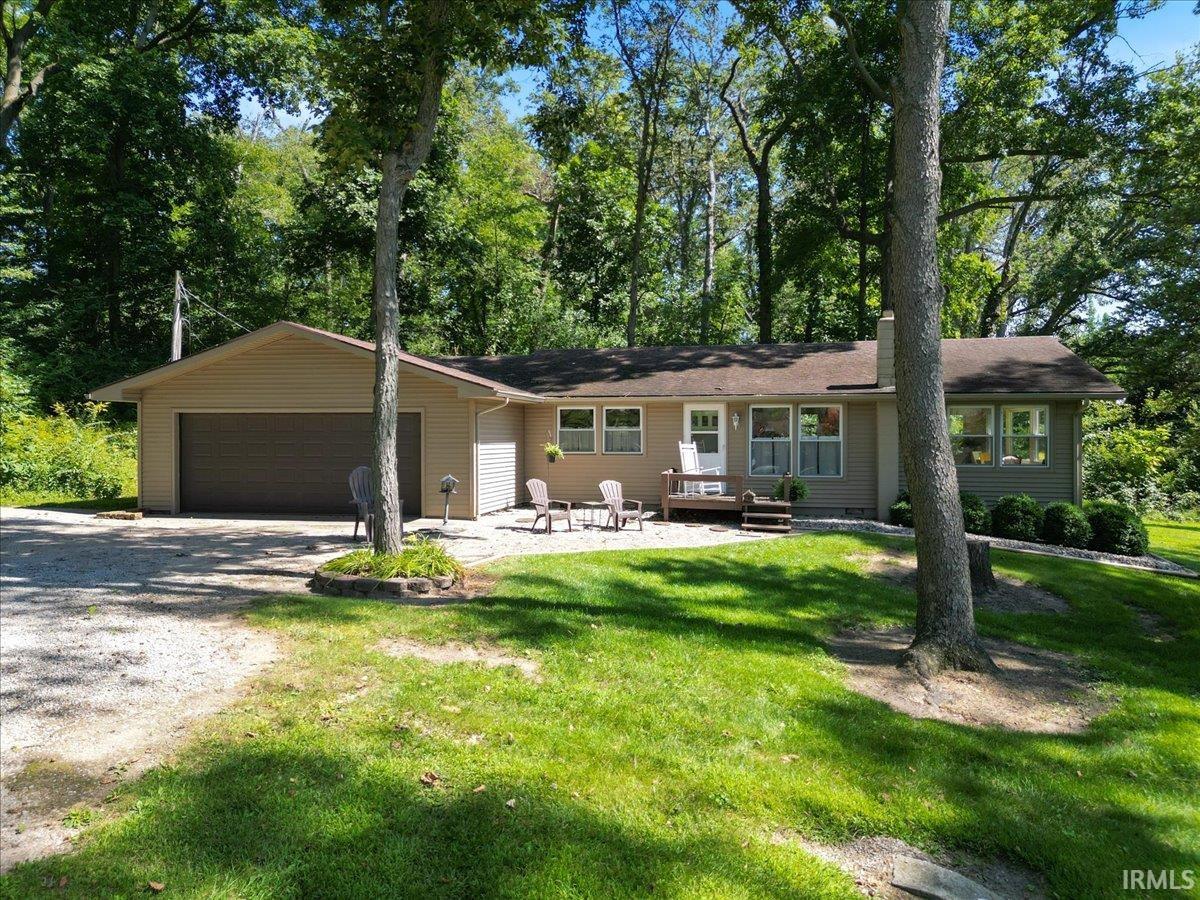 Ranch-style residence featuring a two-car attached garage, light-toned siding, and a front patio with a wood-finish deck