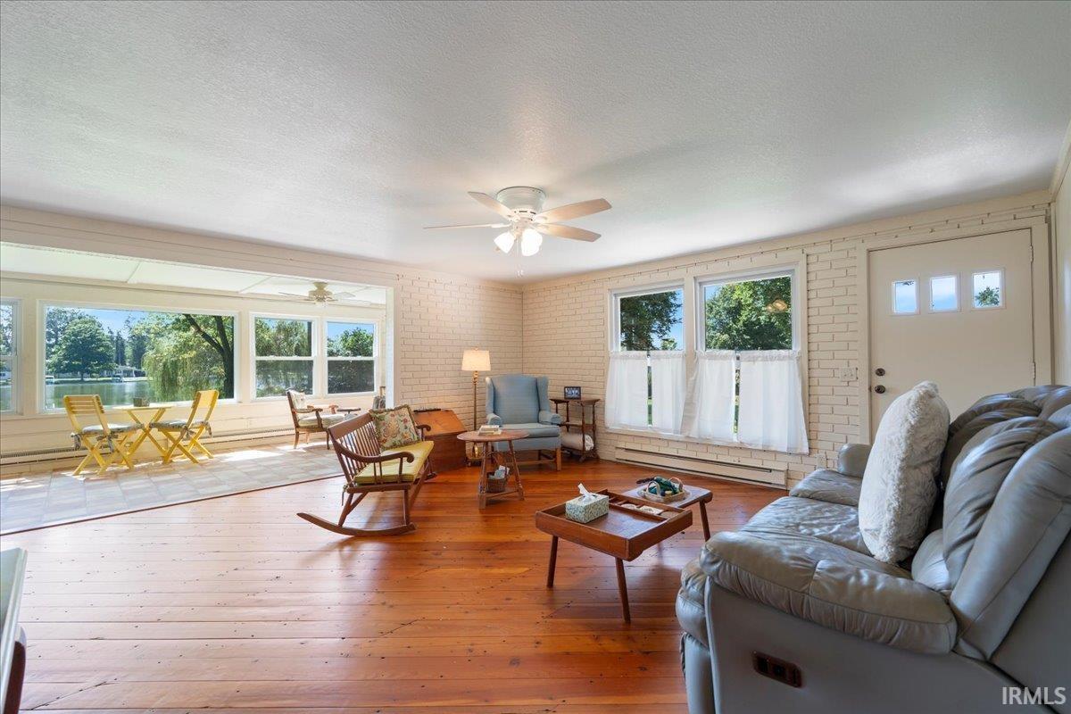 Expansive living area featuring wood flooring, a ceiling fan with integrated lighting, and multiple windows