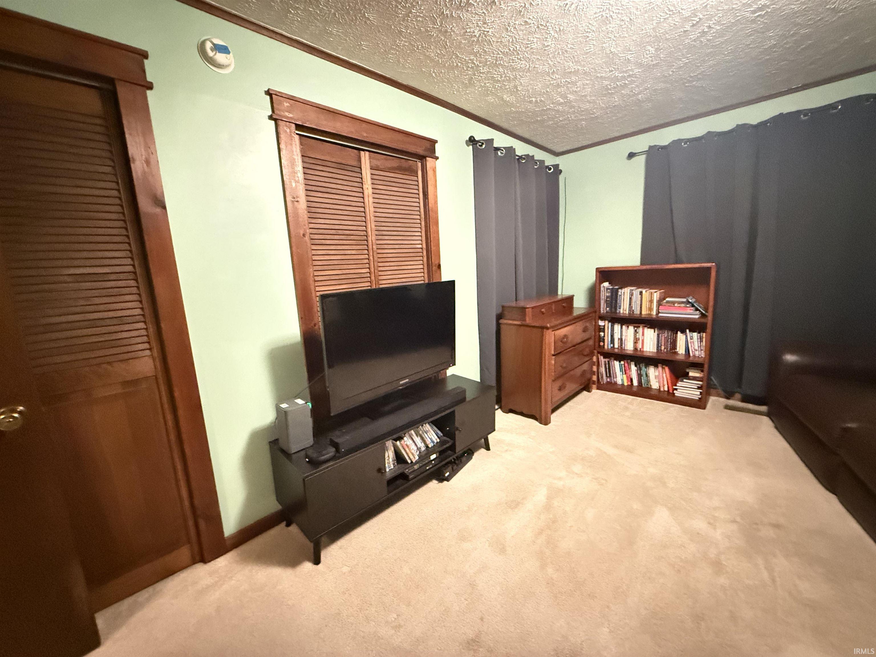 Wood-finish interior doors with louvered panels, wood-trimmed window with louvered blinds, and textured ceiling