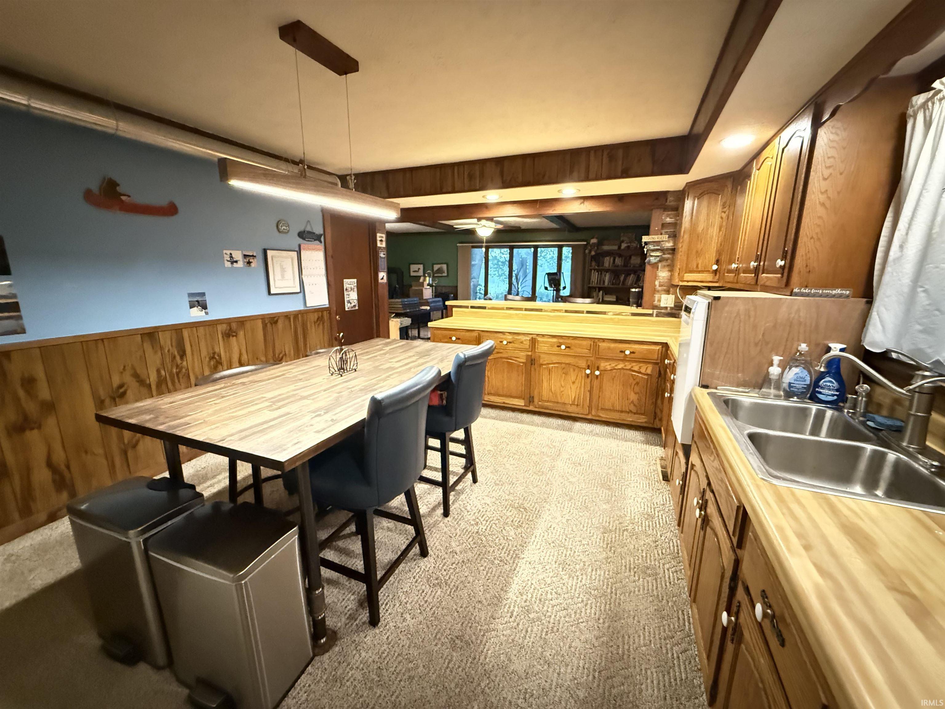 Kitchen area with wood-finish cabinetry, light wood-finish countertops, and a double basin stainless steel sink