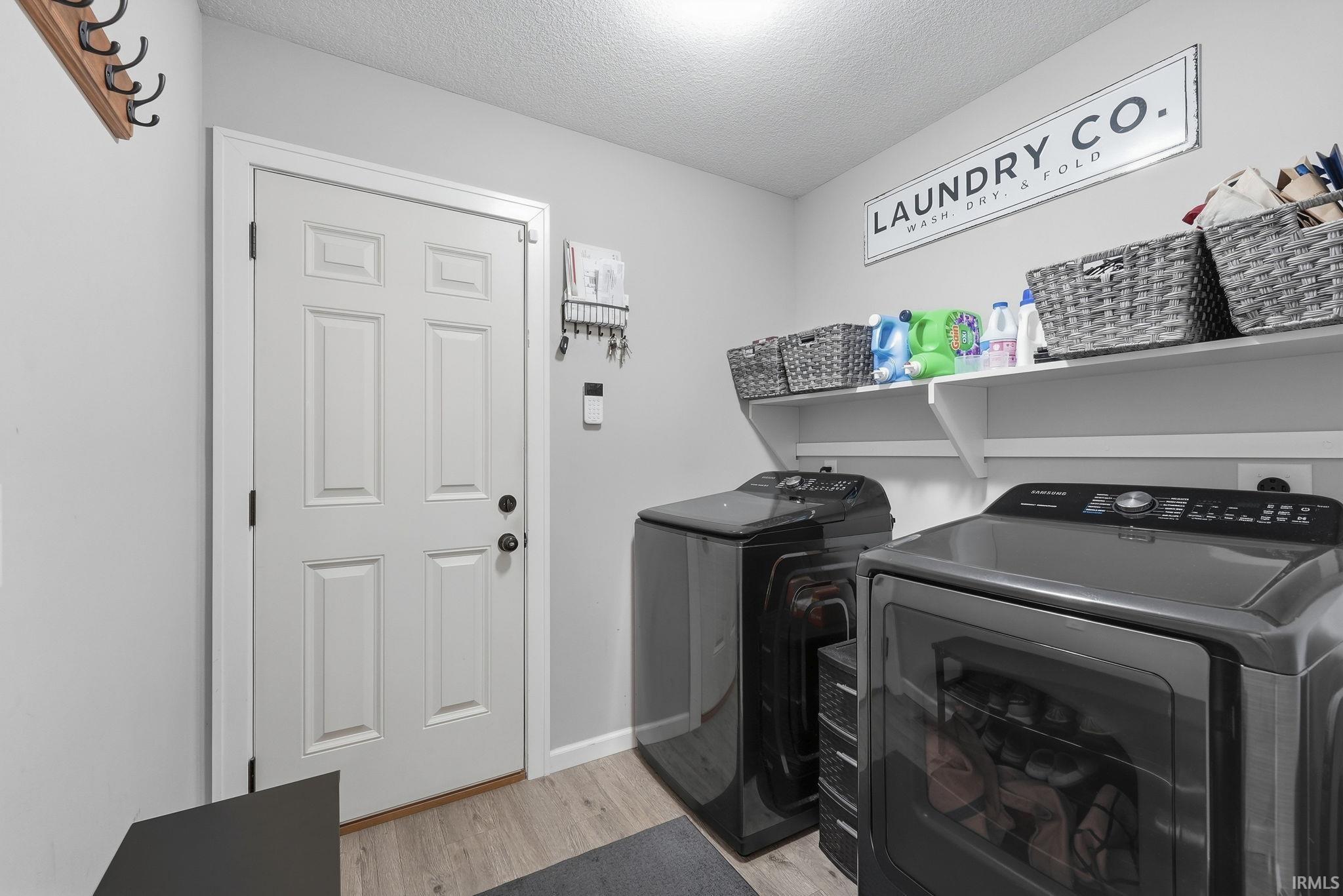 Utility space featuring panel door, wood-finish flooring, and wall-mounted shelving