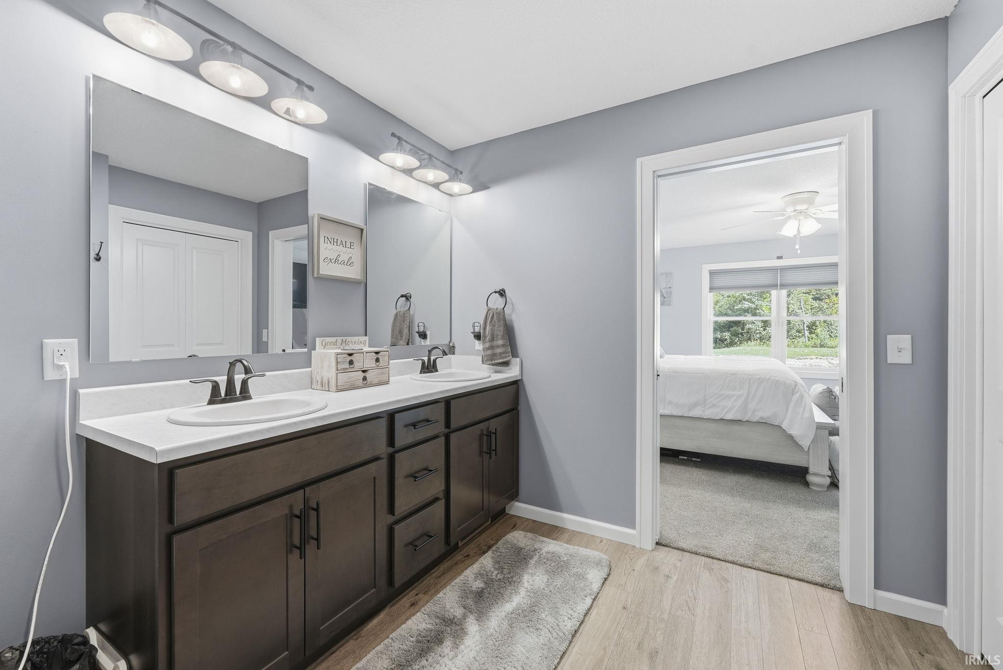 Dual vanity with white countertops, undermount sinks, and dark cabinetry