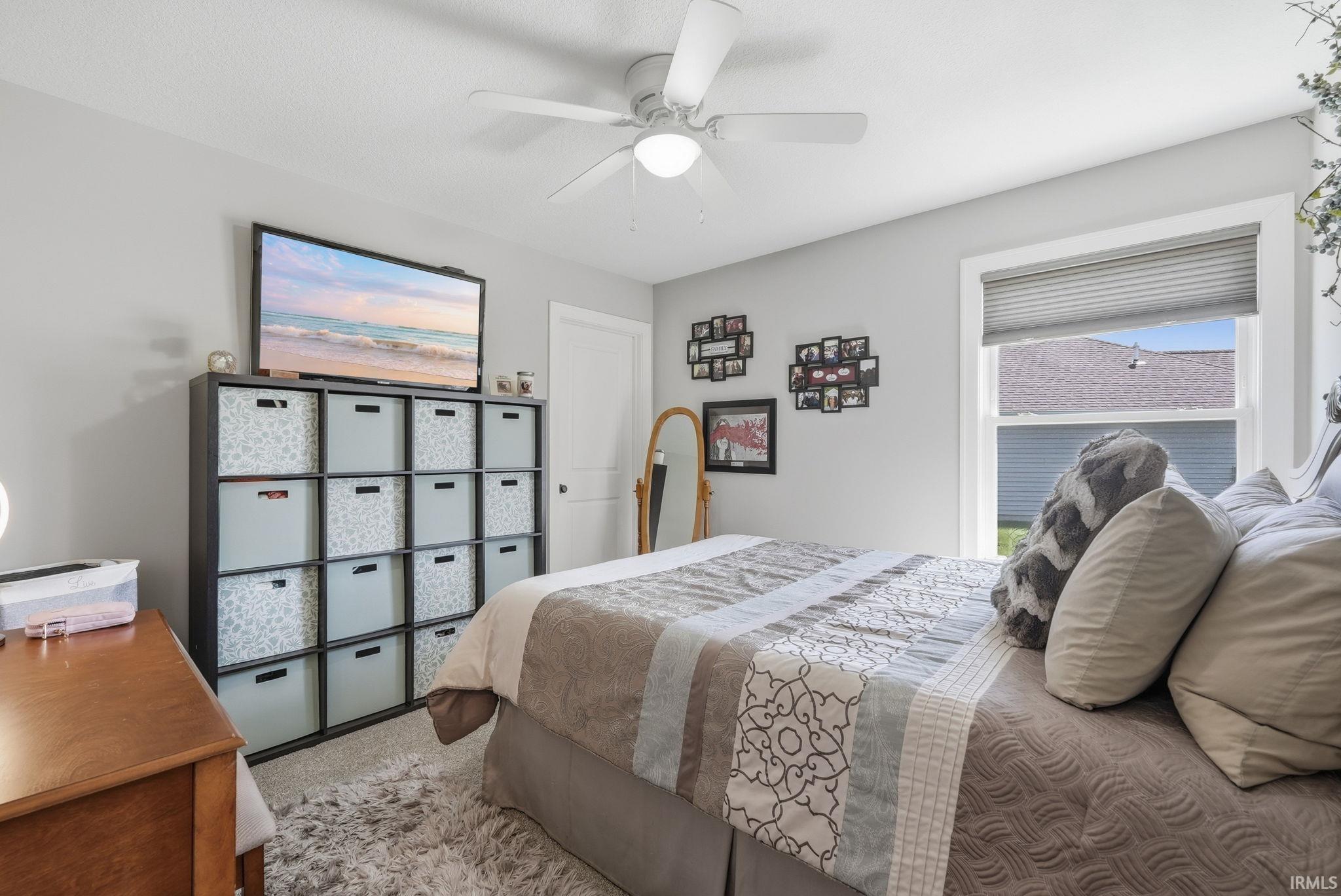 Neutral wall paint, ceiling fan with integrated lighting, wood-finish flooring, and window with privacy blinds