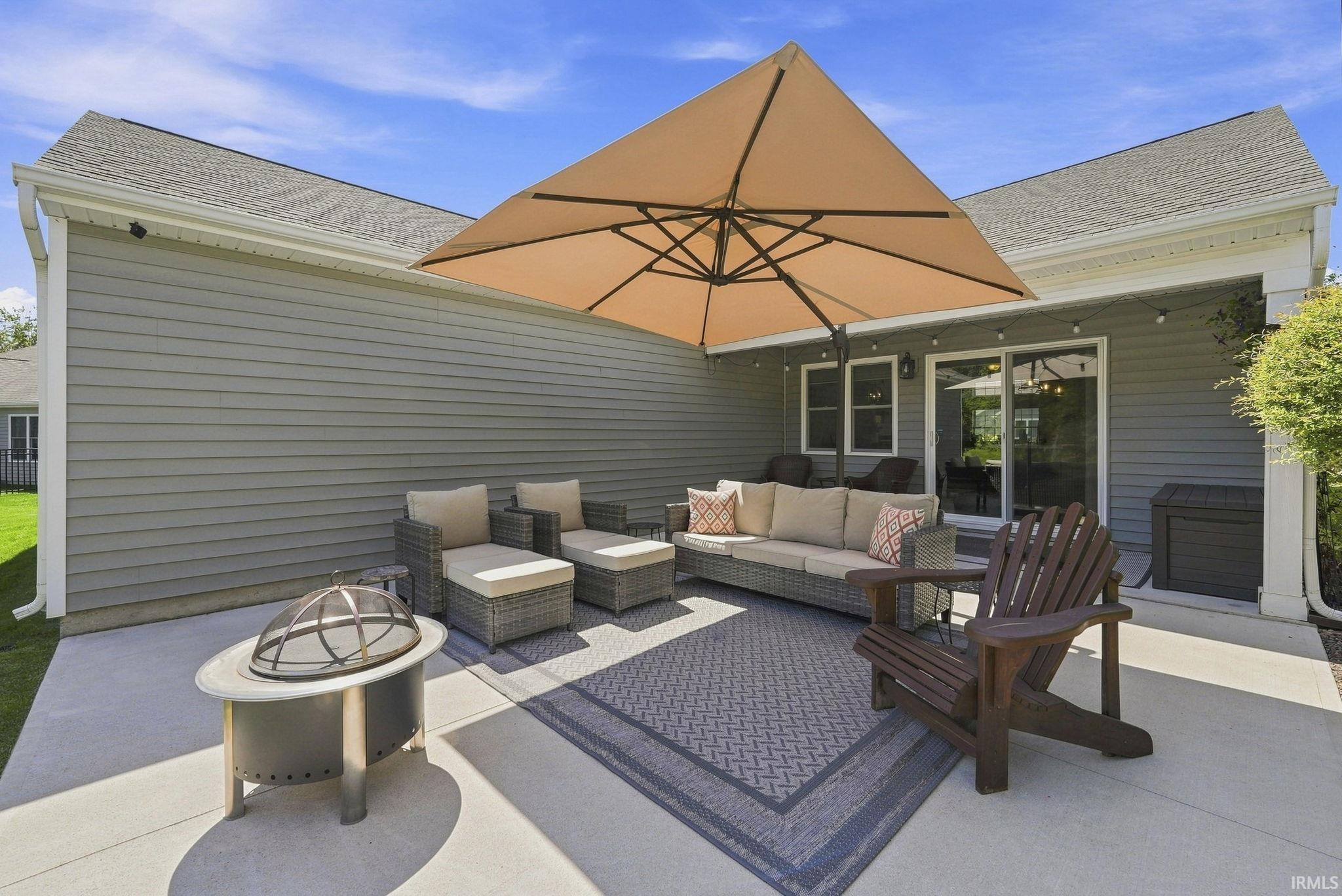 Concrete patio with siding exterior, sliding glass door access, and string lighting