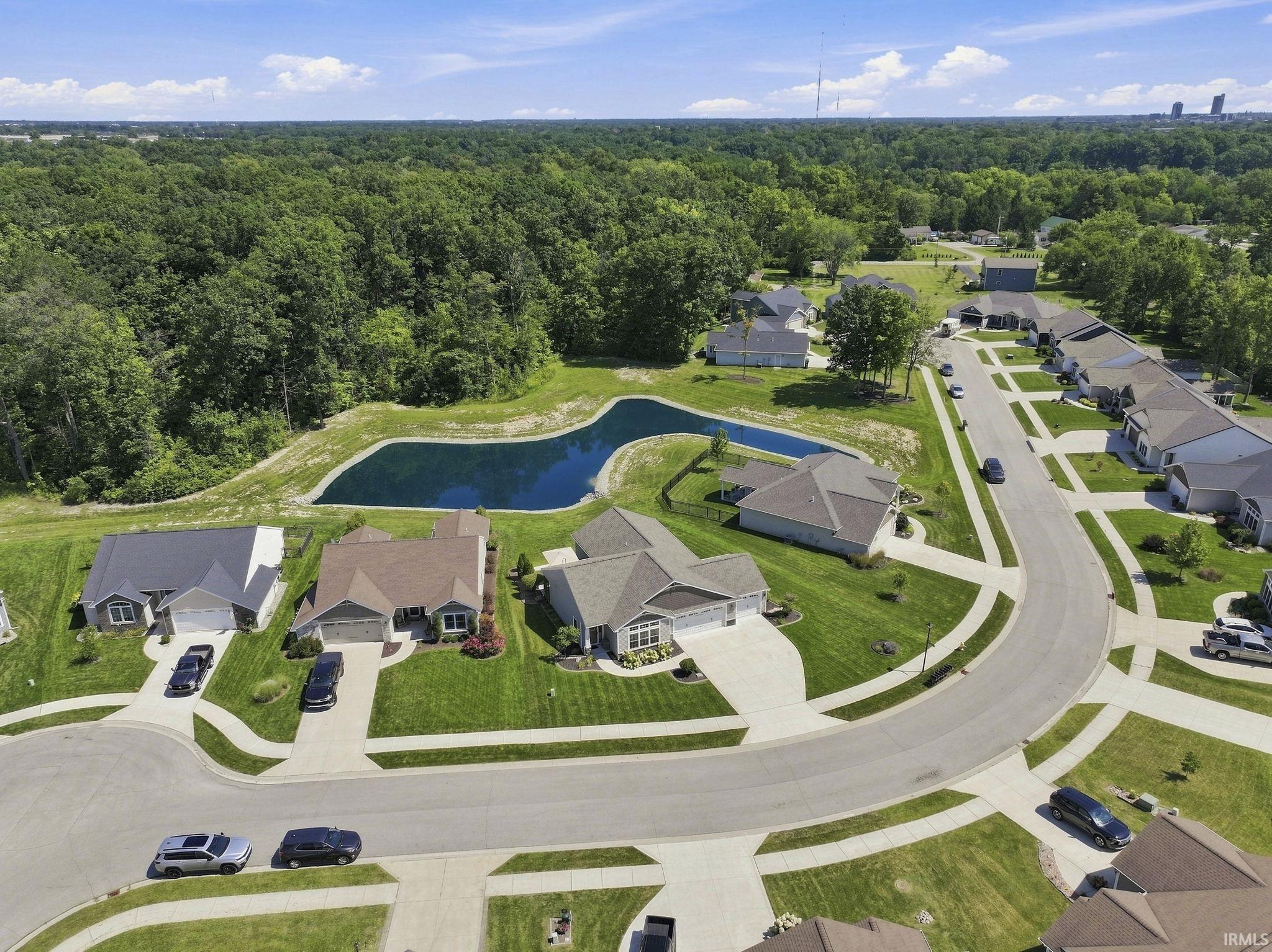 Residential development featuring curved streets, uniform landscaping, and a central water feature