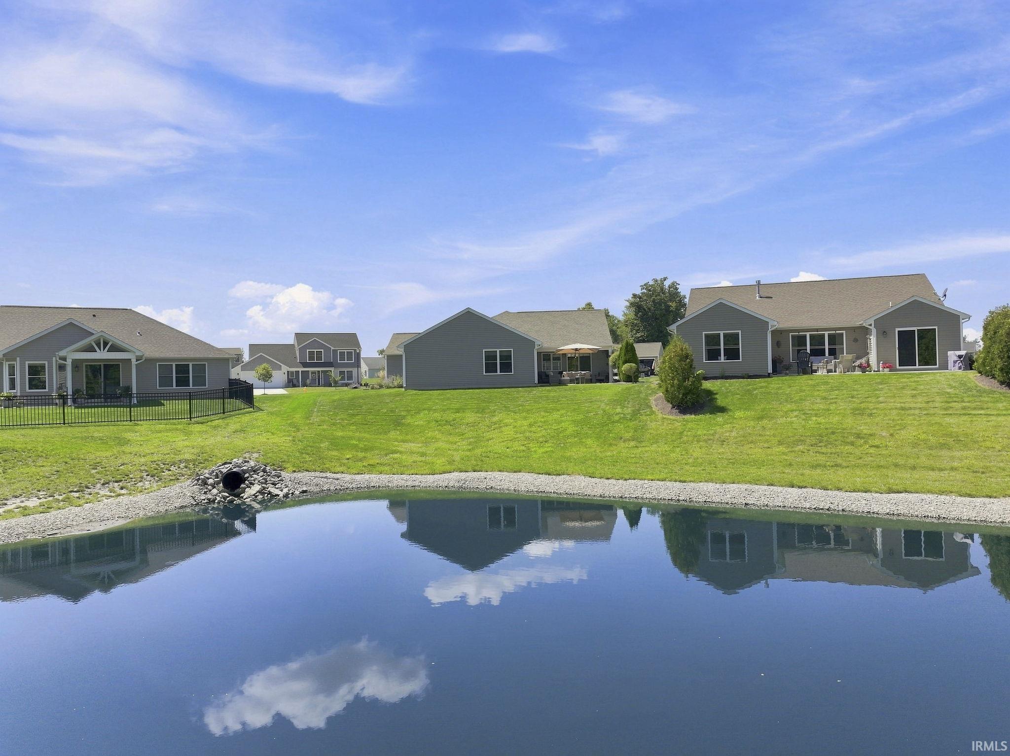 Expansive backyard featuring a manicured lawn, a covered patio, and mature landscaping
