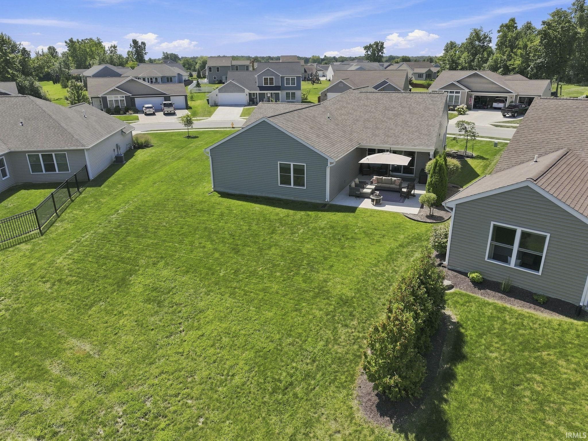 Expansive manicured lawn anchored by mature landscaping and mature evergreen screening