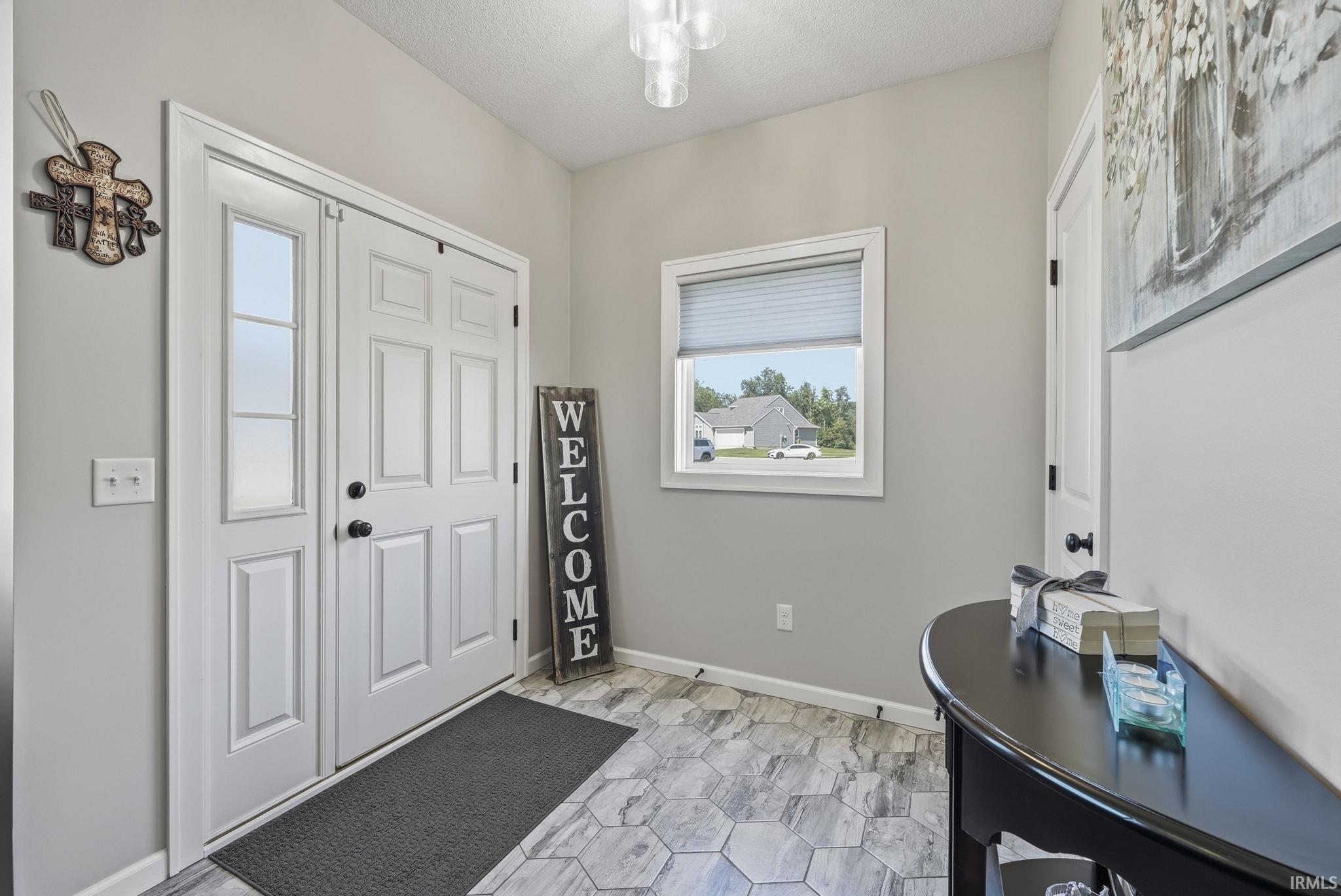 Entryway featuring hexagonal tile flooring, double panel doors with a sidelight, a window with blinds, and neutral wall tones