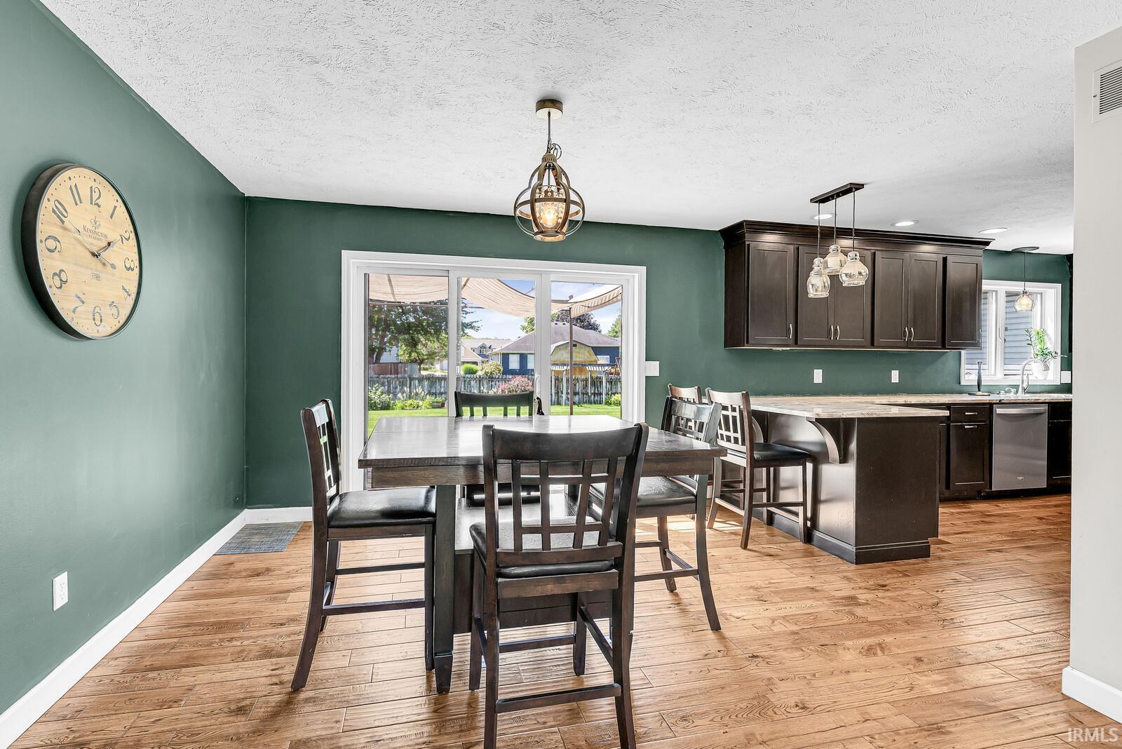 Wood-finish flooring throughout, dark cabinetry with crown molding, granite countertops, and stainless steel appliances