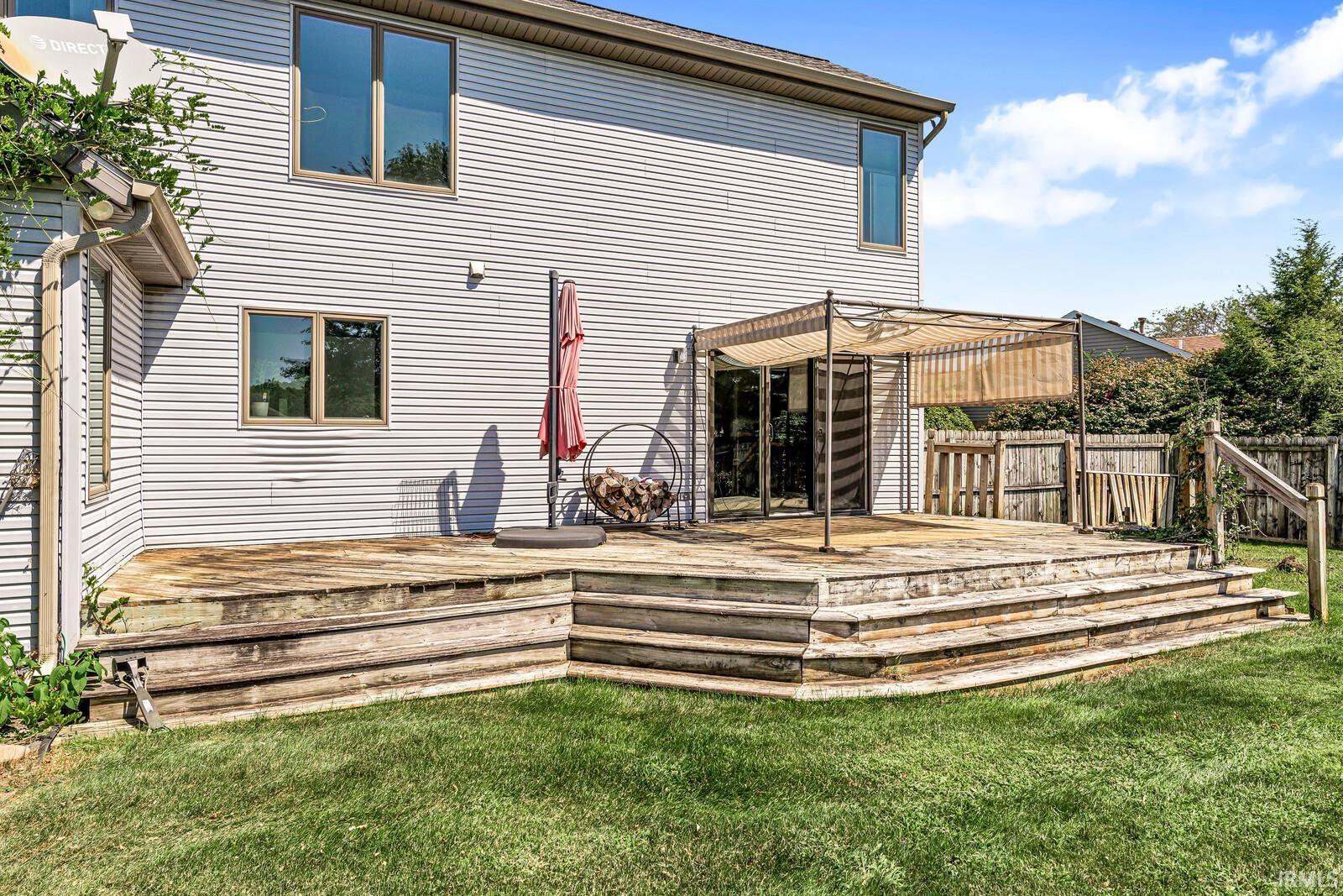Multi-level wood deck with a built-in pergola and access to the home's siding exterior