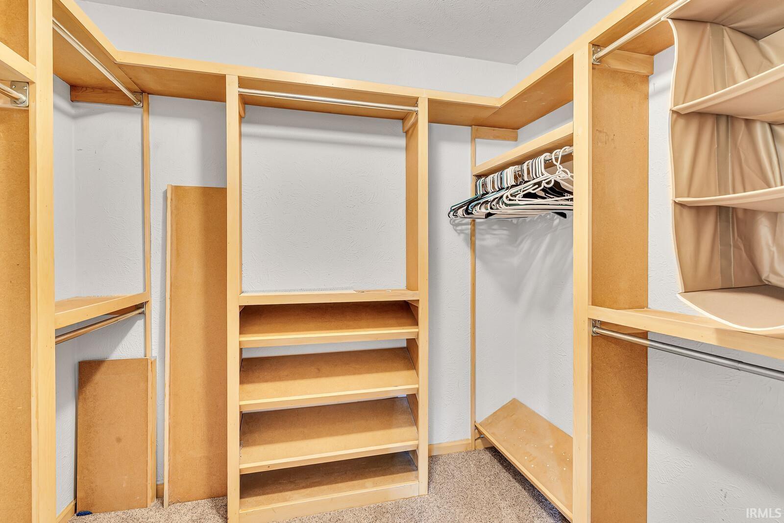 Custom closet system with multiple shelving units and hanging rods