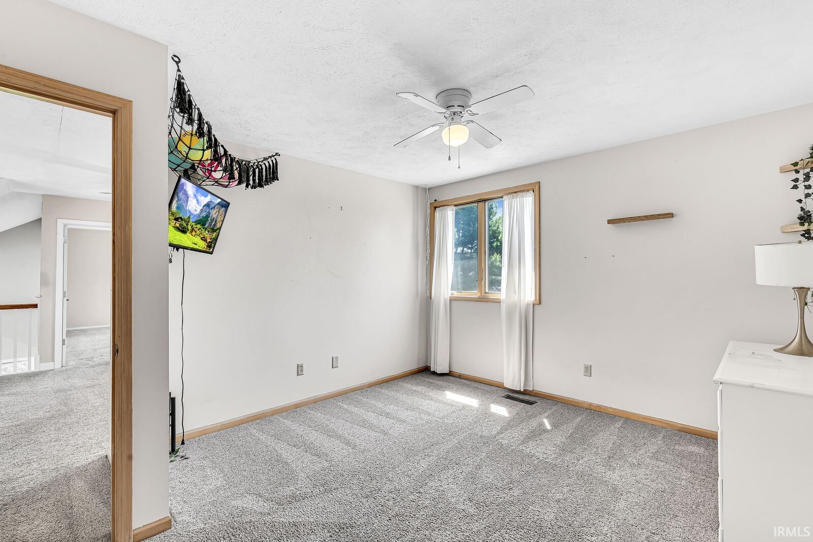 Wall-to-wall carpeting, a window with wood trim, and a ceiling fan with integrated lighting