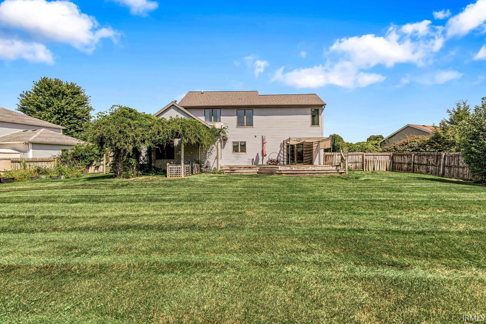 Expansive backyard featuring a large grassy area, a multi-level deck, and a covered patio structure