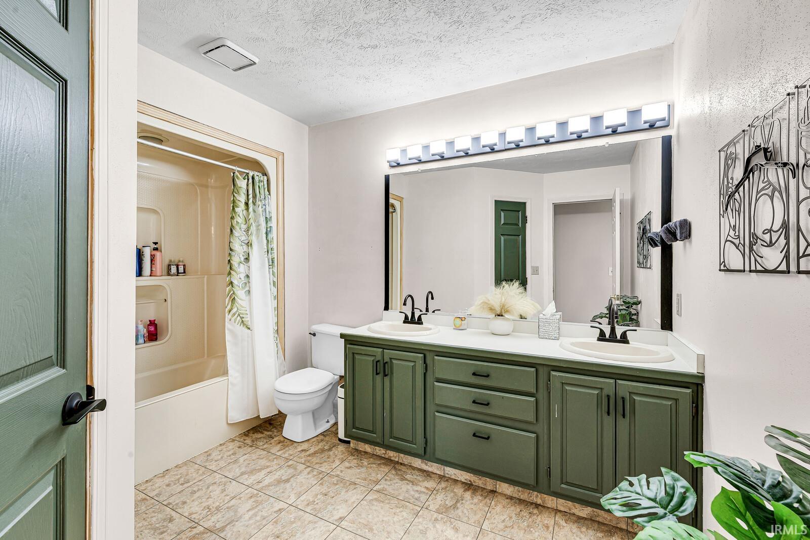 Dual vanity with matte black hardware, white countertop, and green cabinetry