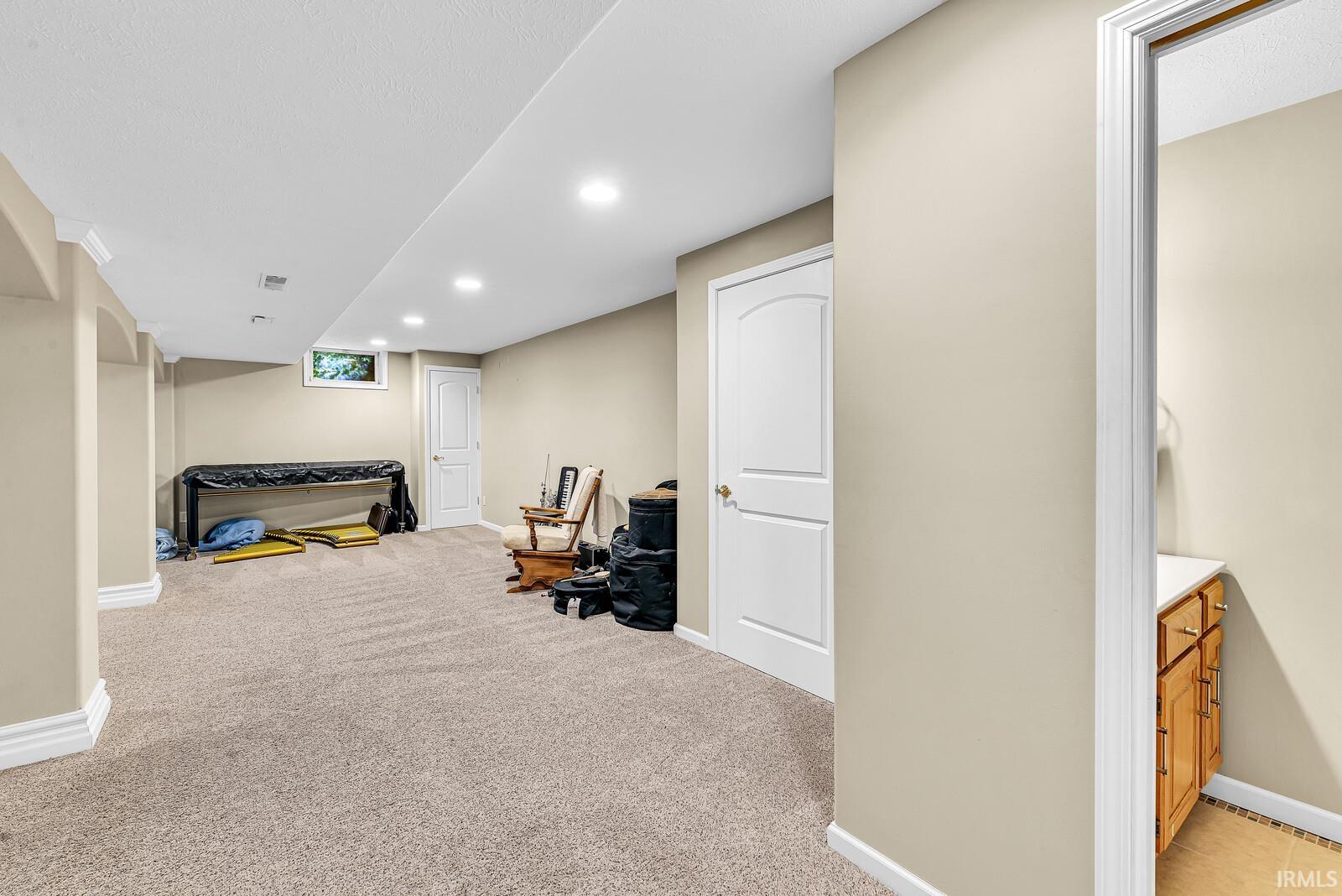 Recessed lighting, neutral-toned walls, and soft pile carpeting