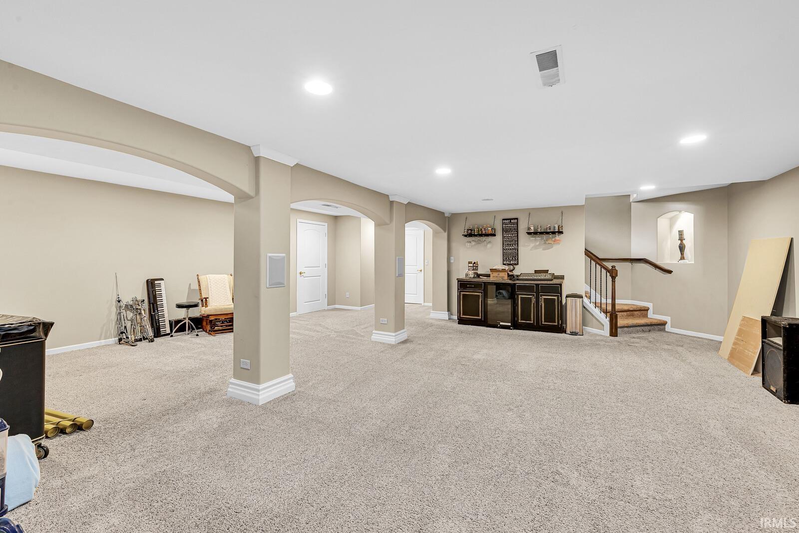 Expansive carpeted area featuring recessed lighting, archways, and a built-in wet bar with shelving