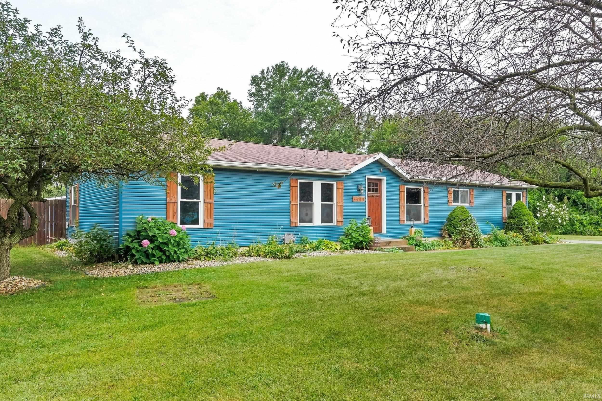 Blue siding exterior with contrasting brown shutters, an orange entry door, and a brown shingle roof
