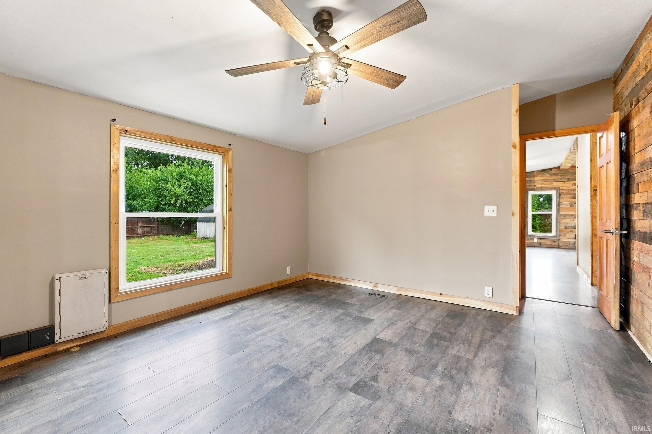 Wood-finish flooring with neutral wall paint and a wood-paneled accent wall