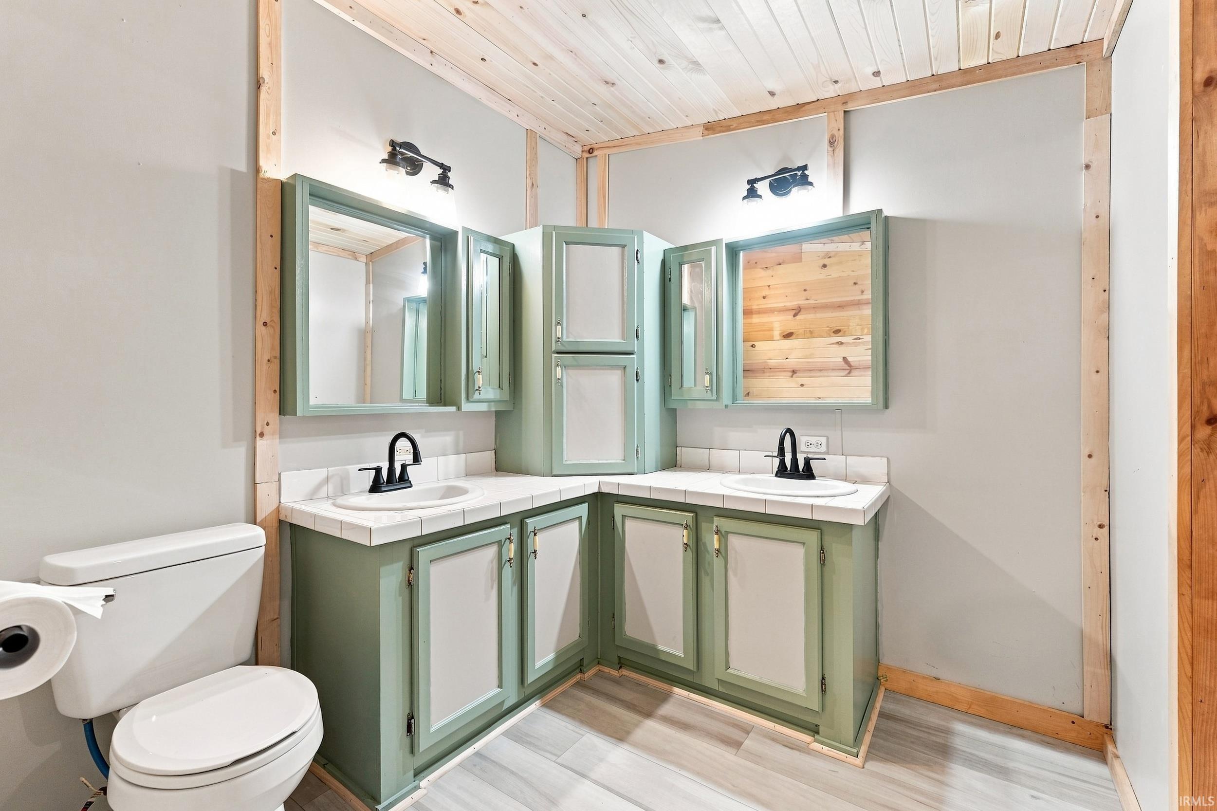 Dual vanity with green cabinetry, white tiled countertops, and black hardware