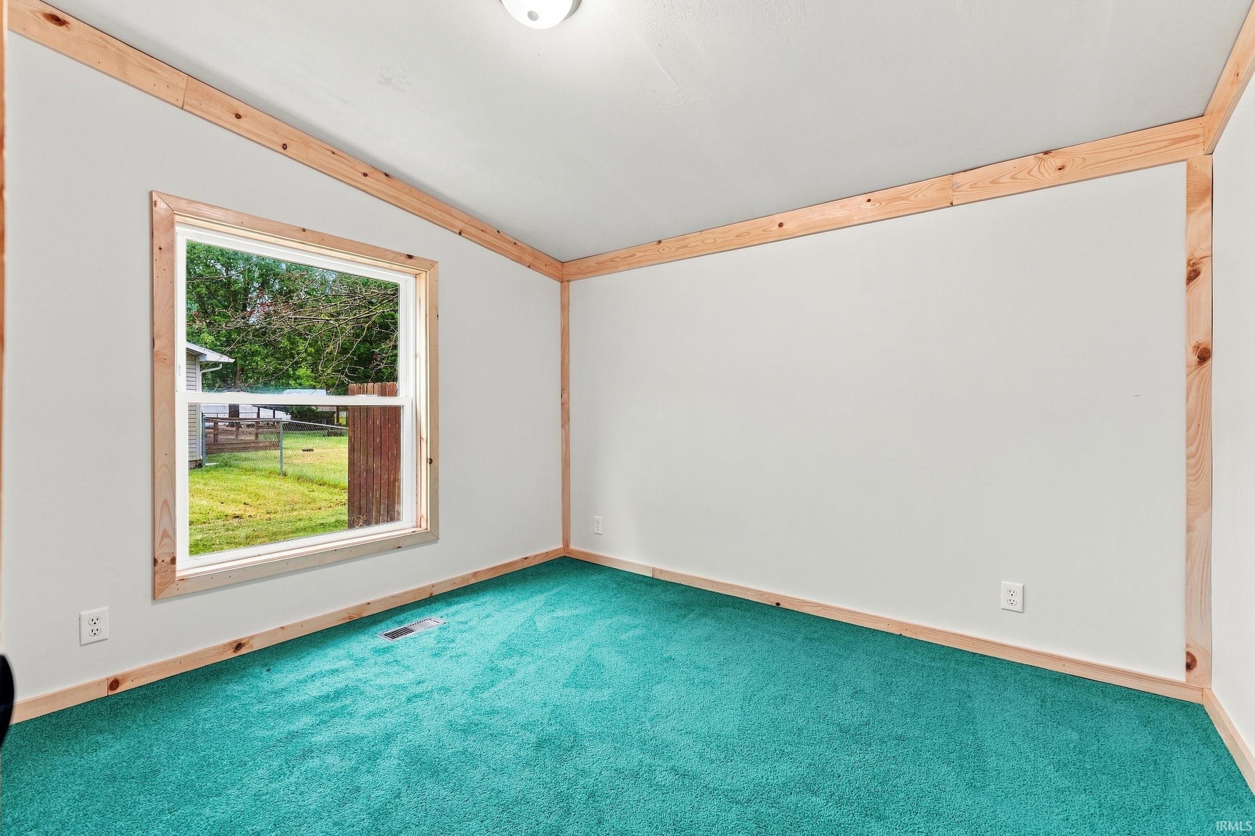 Wall-to-wall carpeting, wood-trimmed window, and wood-trimmed walls