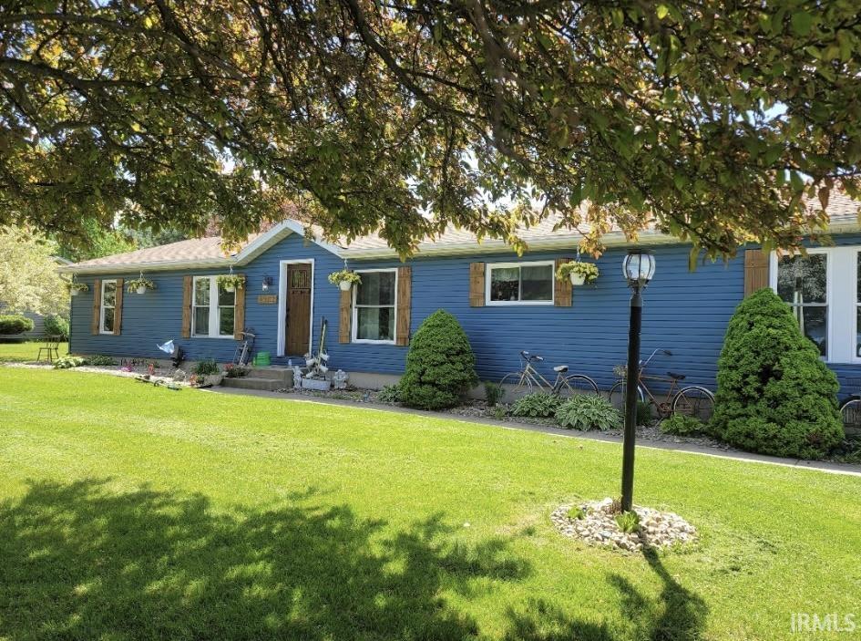 Blue horizontal siding, a light brown entry door, and white frame windows with wood-finish shutters