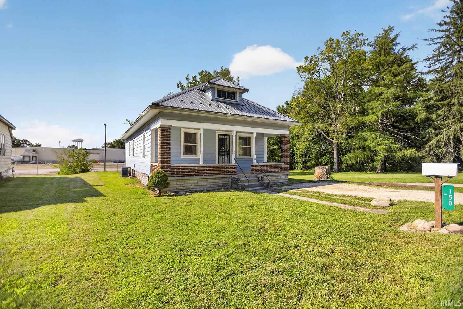 Light blue siding exterior with brick accents, covered front porch, and a dormer window
