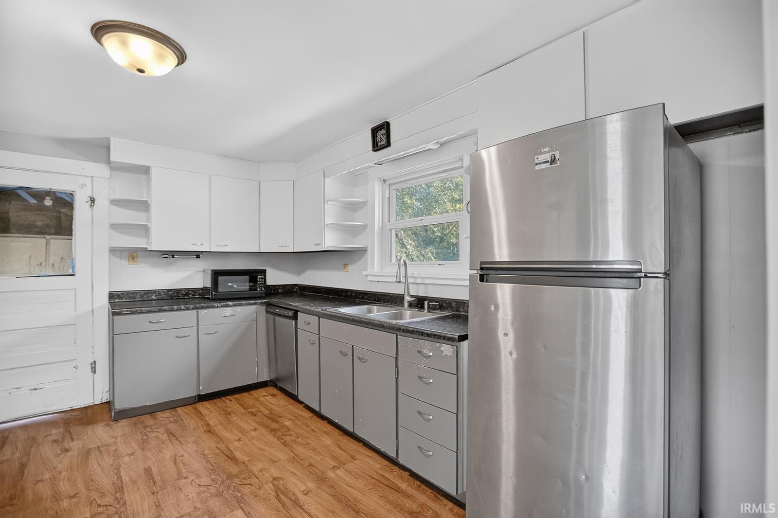 Kitchen featuring vinyl flooring, white cabinetry, dark countertops, and stainless steel appliances