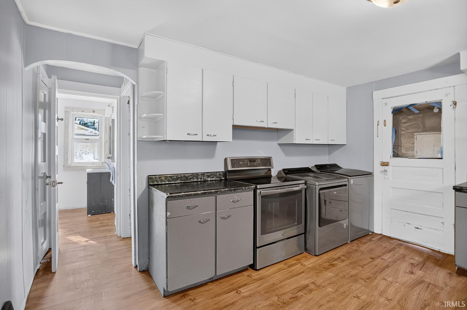 White upper cabinetry, stainless steel range, washing machine and dryer