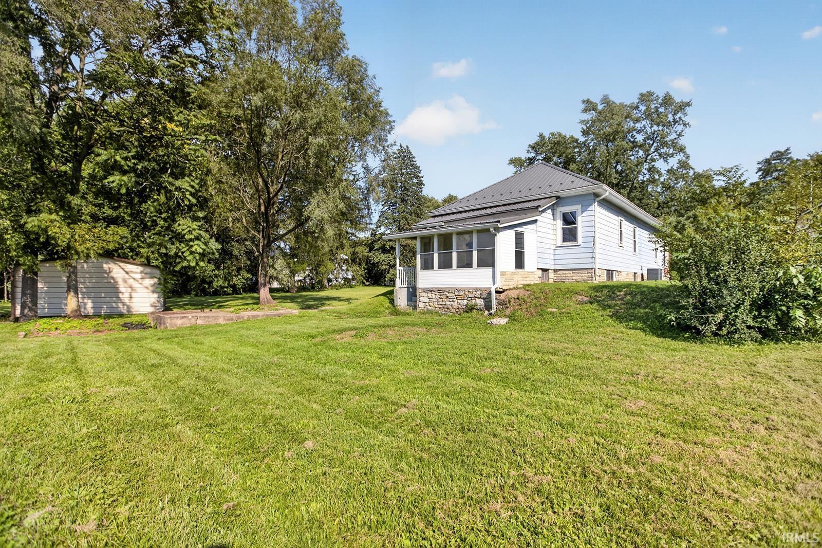 Light blue siding exterior with a dark roof, stone foundation, and an enclosed porch