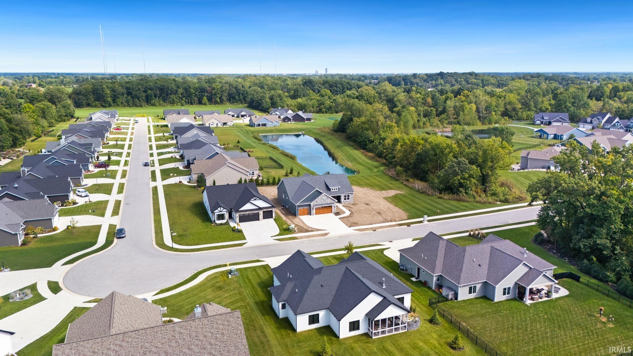 Aerial view of an established residential community featuring new construction homes with modern architectural design, manicured lawns, and tree-lined streetscapes