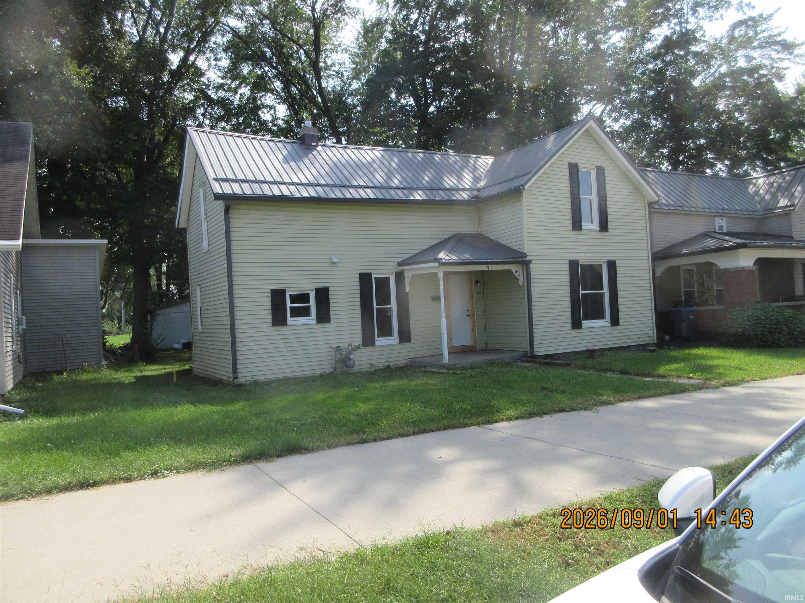 Light-colored siding exterior with a dark metal roof