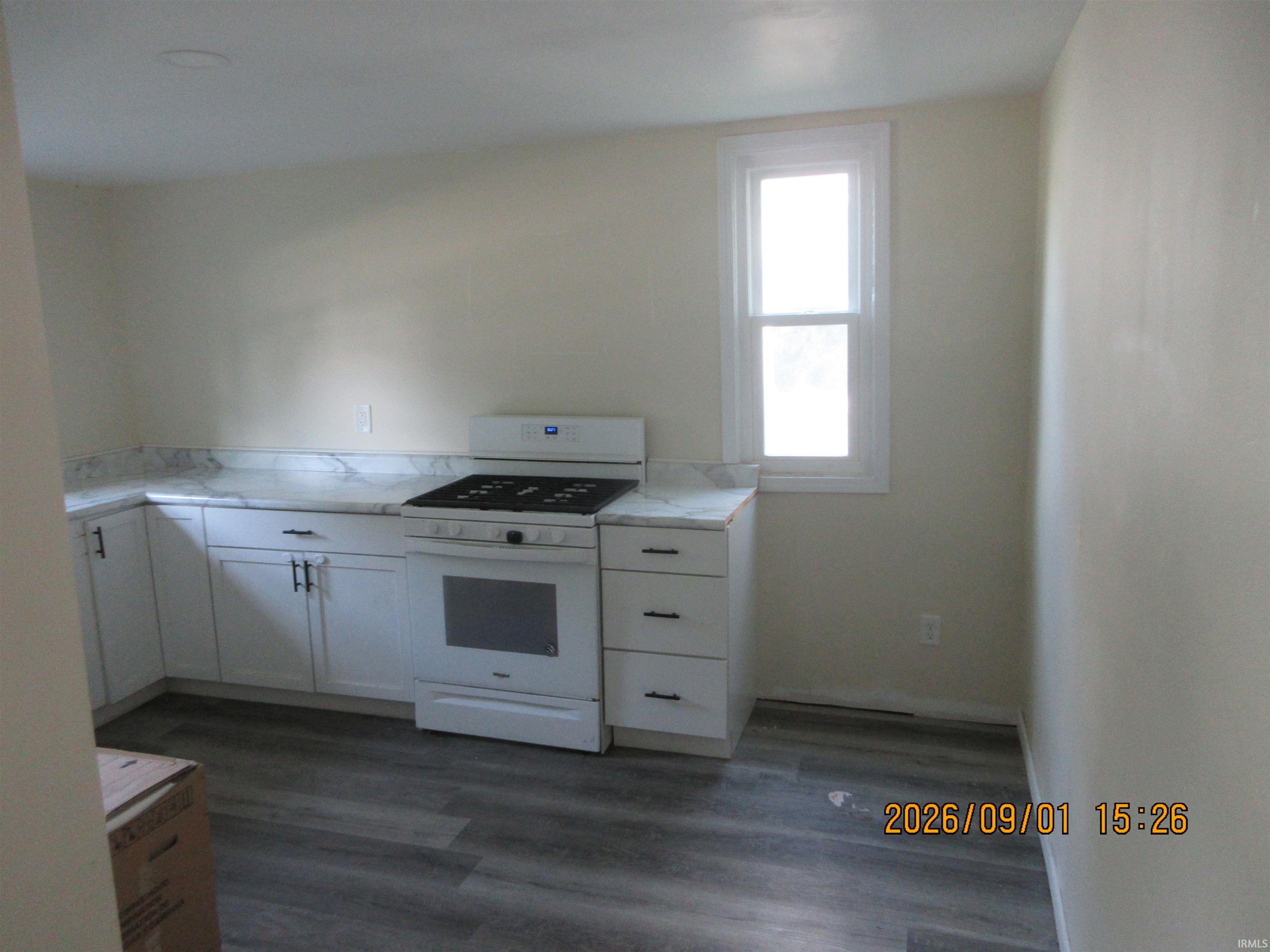 Kitchen featuring white cabinetry with dark hardware, a white range, light-toned countertops, and wood-finish flooring
