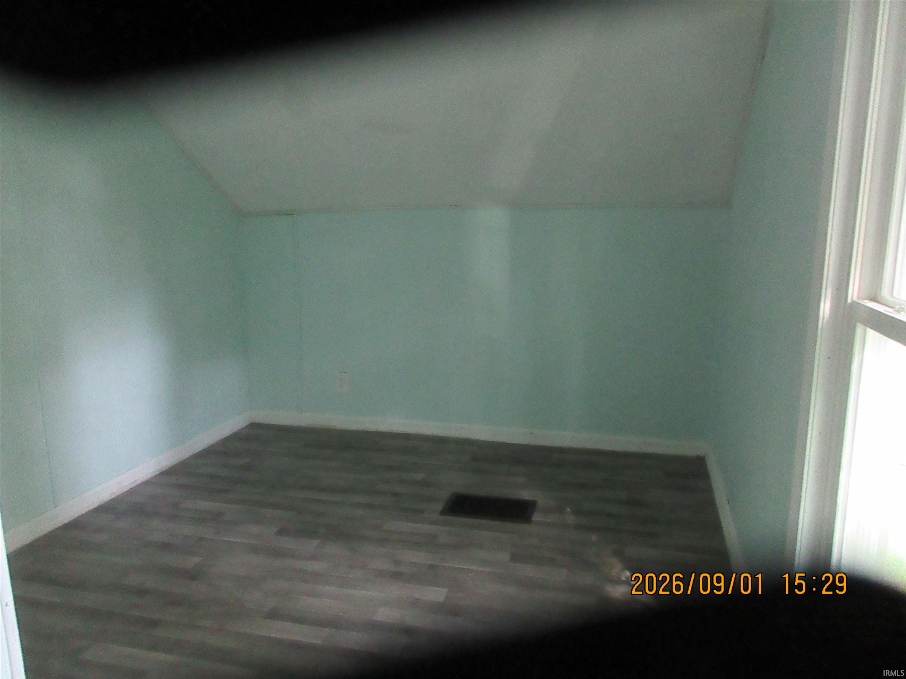 Wood-finish flooring with light blue wall paneling, featuring a window with white trim