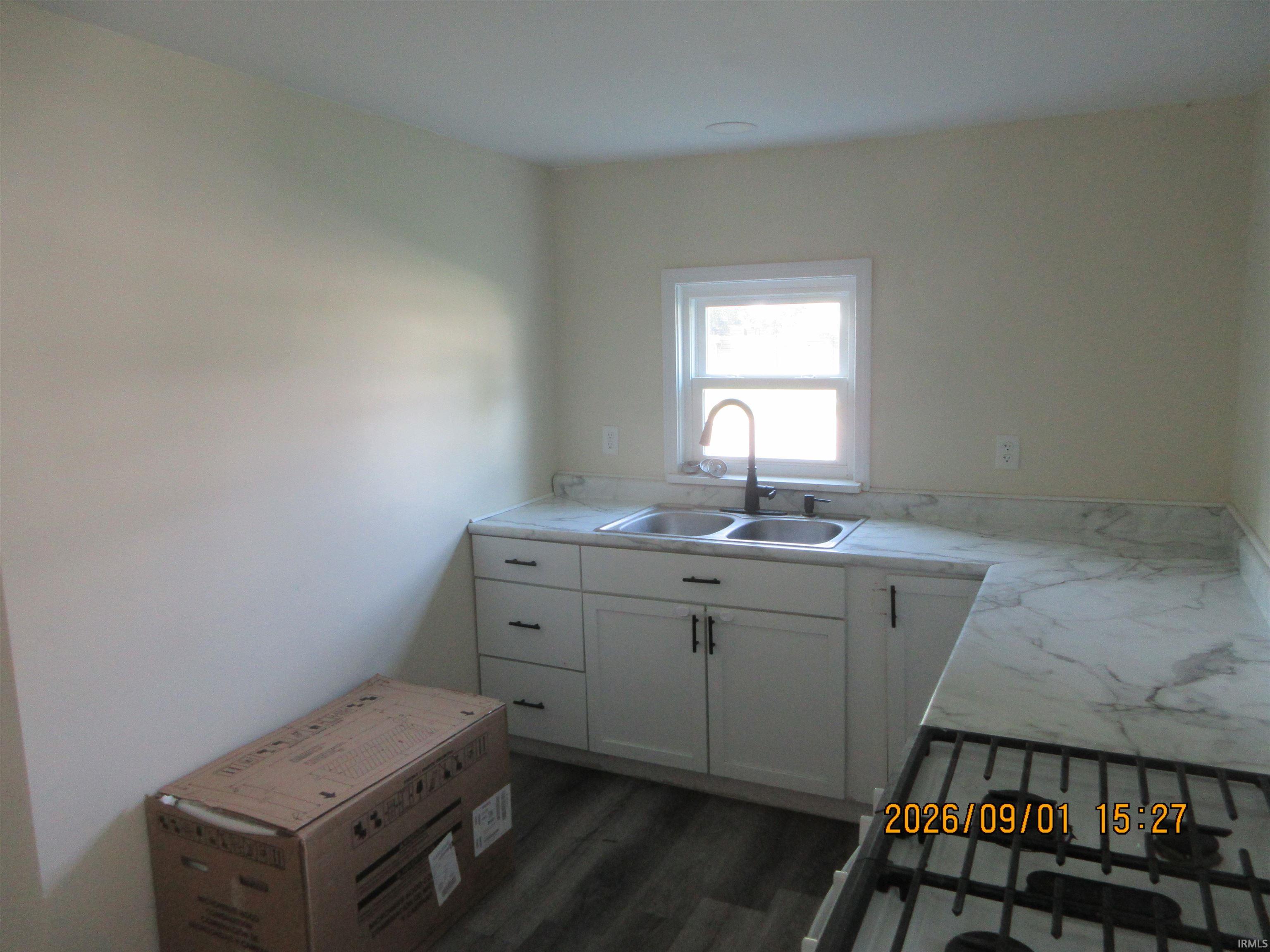 Kitchen featuring white cabinetry, a double basin sink, black faucet, and white marble-look countertops
