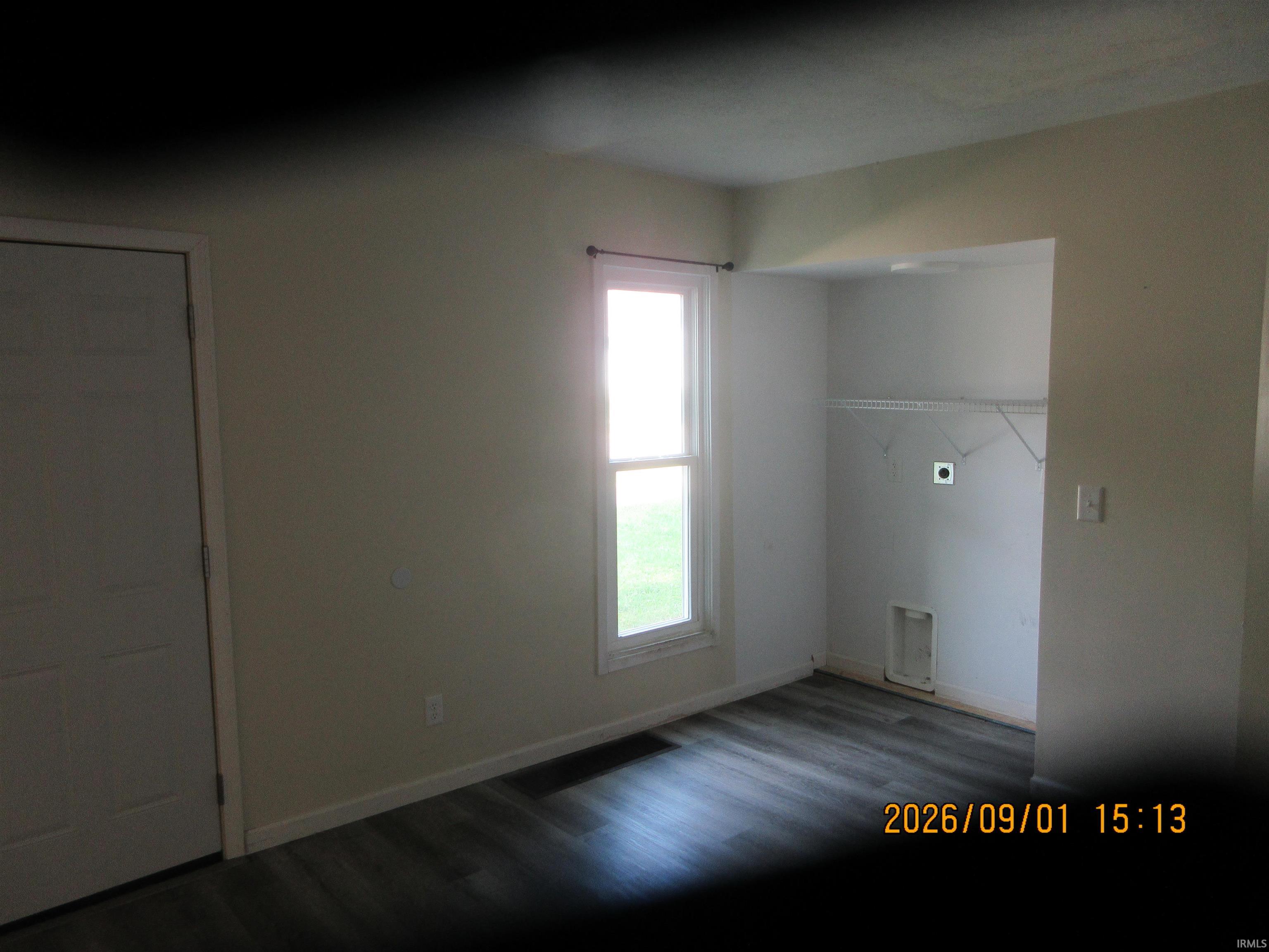 Wood-finish flooring, single window, white interior door, and a built-in shelf